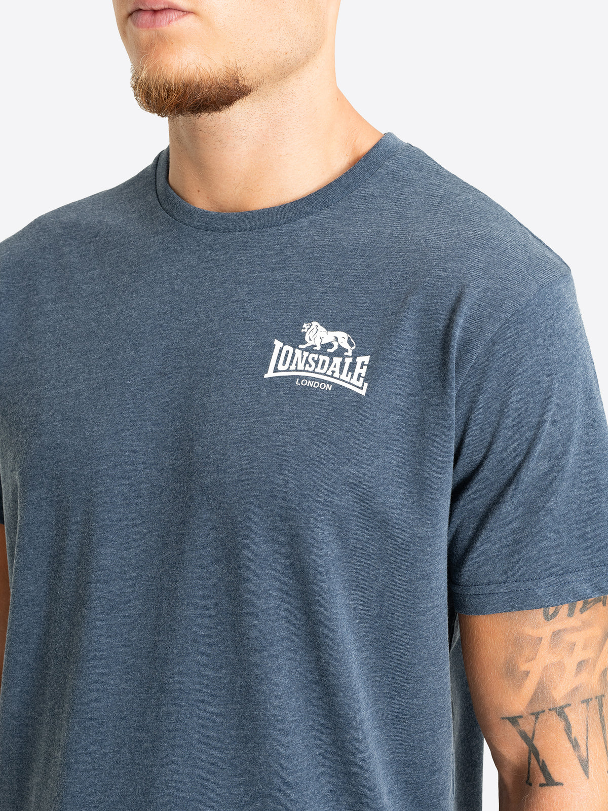 Detailaufnahme des kleinen weissen Lonsdale London Logo-Prints auf der Brust eines blau melierten Herren-T-Shirts.