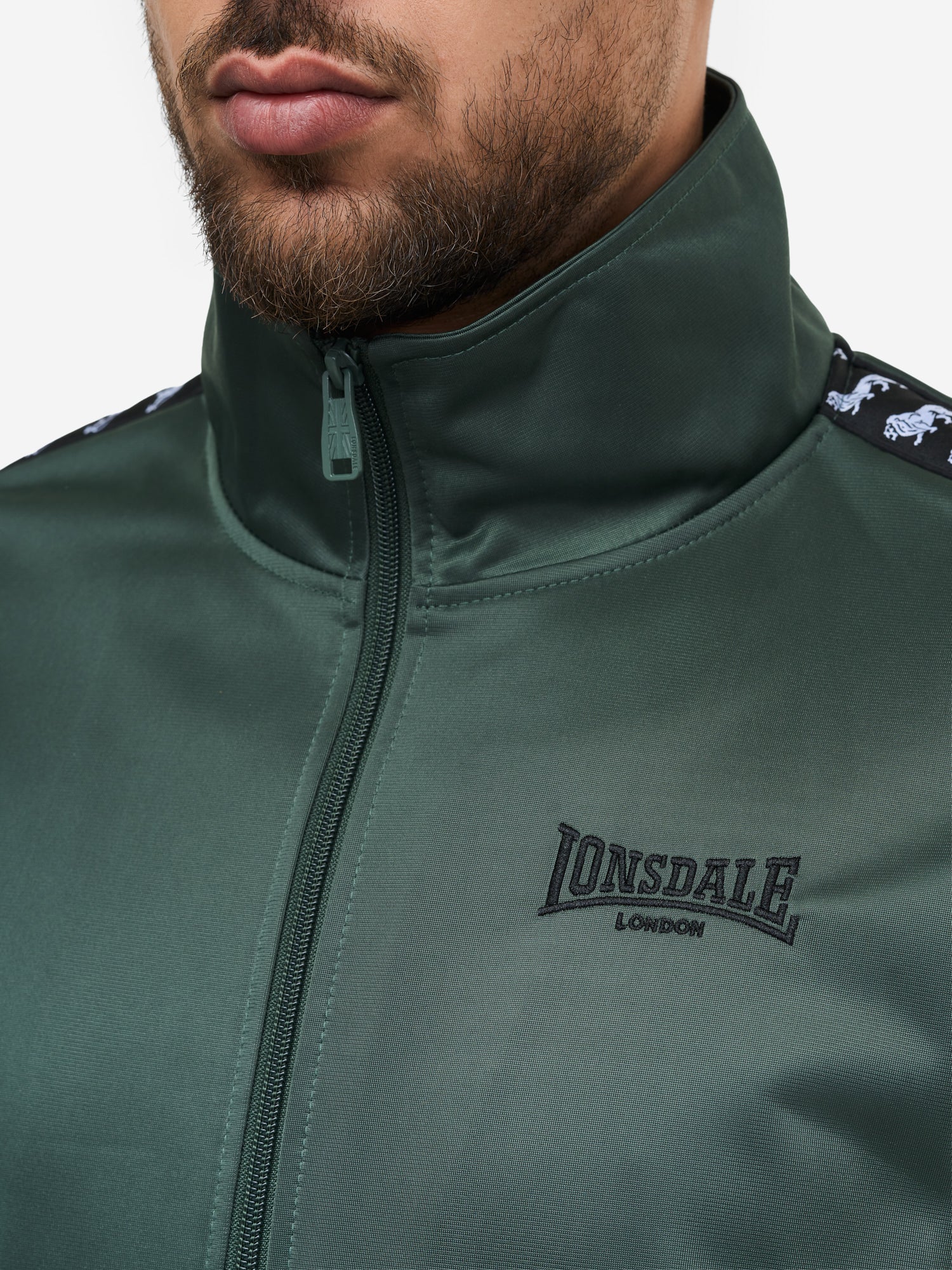 Detail: Lonsdale Logo-Stickerei und Reisserschlusstasche am Wyberton Trainingsanzug Oliv