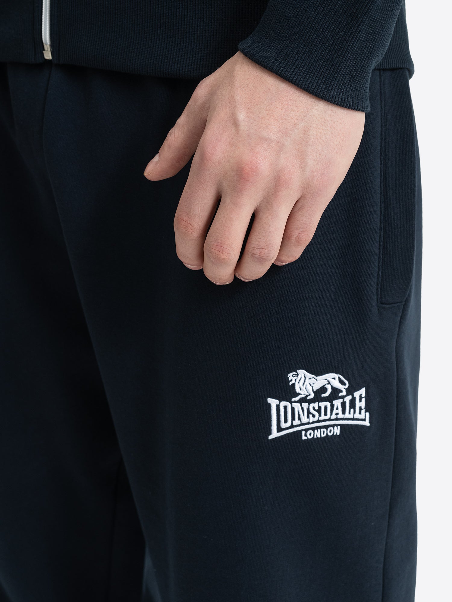 Lonsdale London Logo Stickerei auf dunkelblauer Herren Jogginghose Detailansicht.
