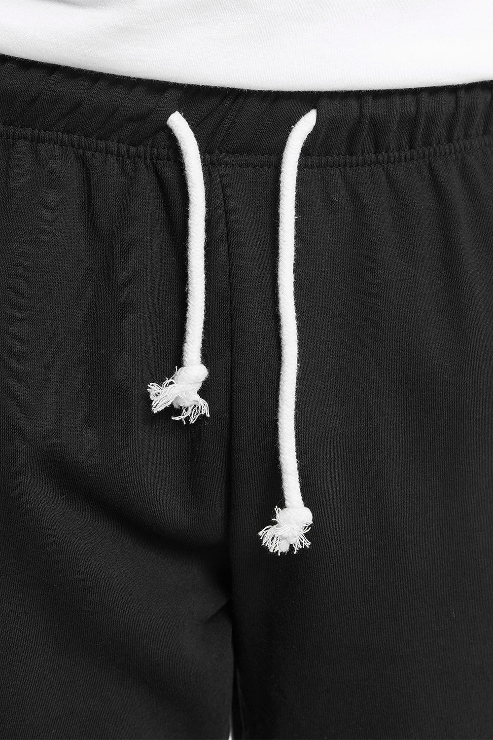 Nahaufnahme der weißen Kordelzüge am Bund der schwarzen Lonsdale Jogginghose.
