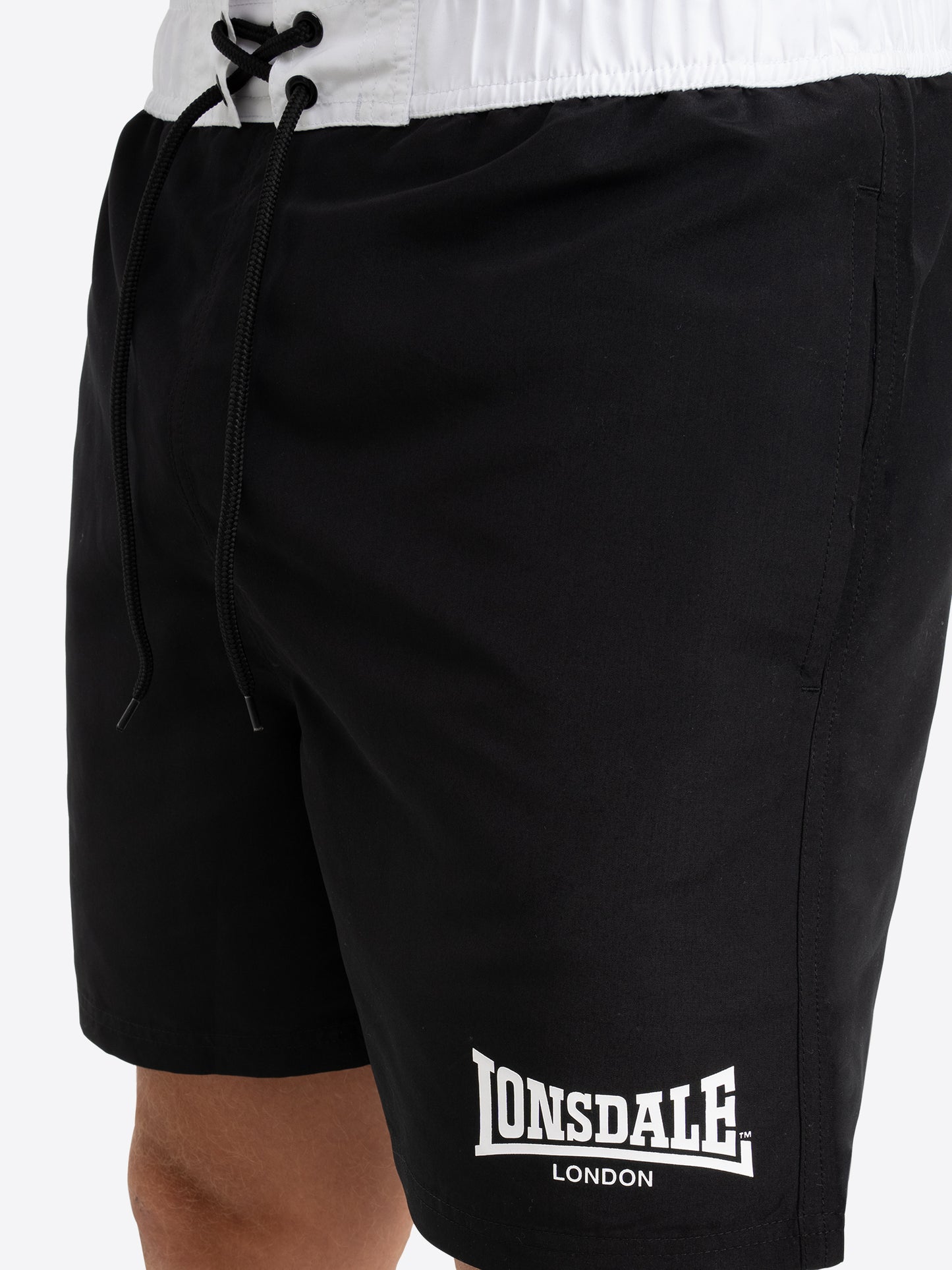 Detail der Lonsdale Shorts Schwarz: Seitliche Eingriffstasche und hochwertiger Logo-Druck auf schnelltrocknendem Polyester.