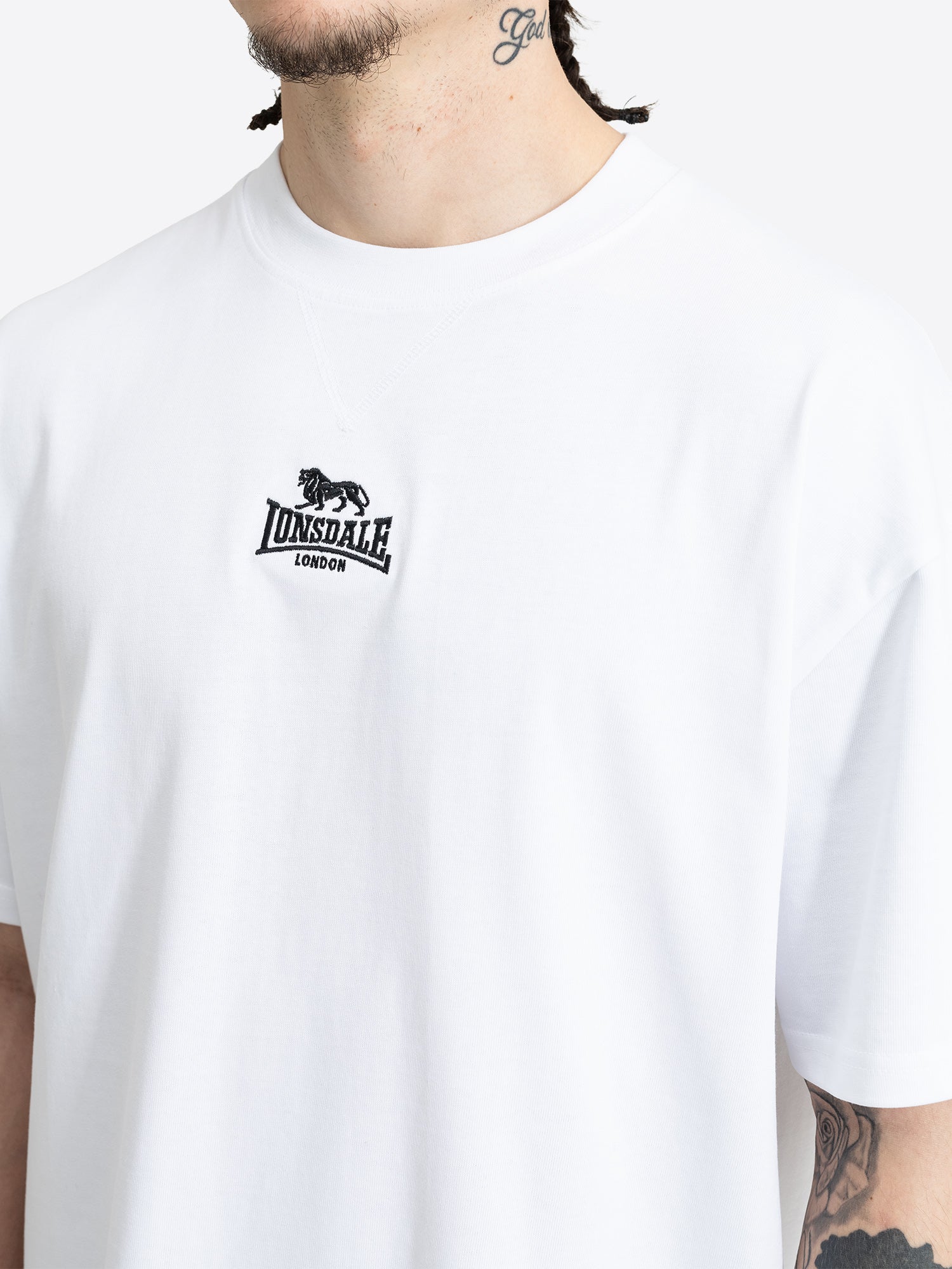 Nahaufnahme der schwarzen Lonsdale Logo-Stickerei auf der Brust des weissen T-Shirts.