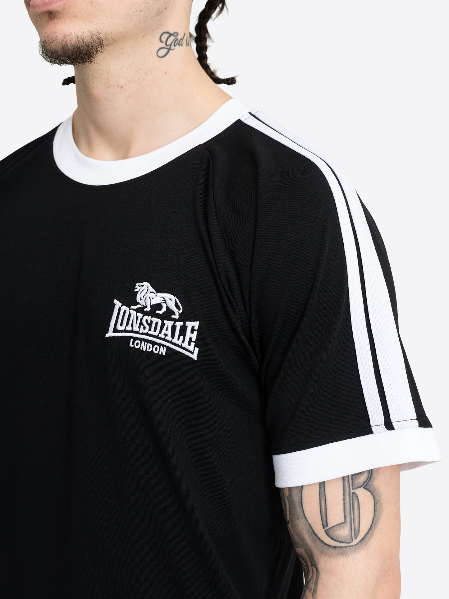 Nahaufnahme der kleinen Lonsdale Logo-Stickerei auf der Brust des schwarzen Baumwoll-Shirts.