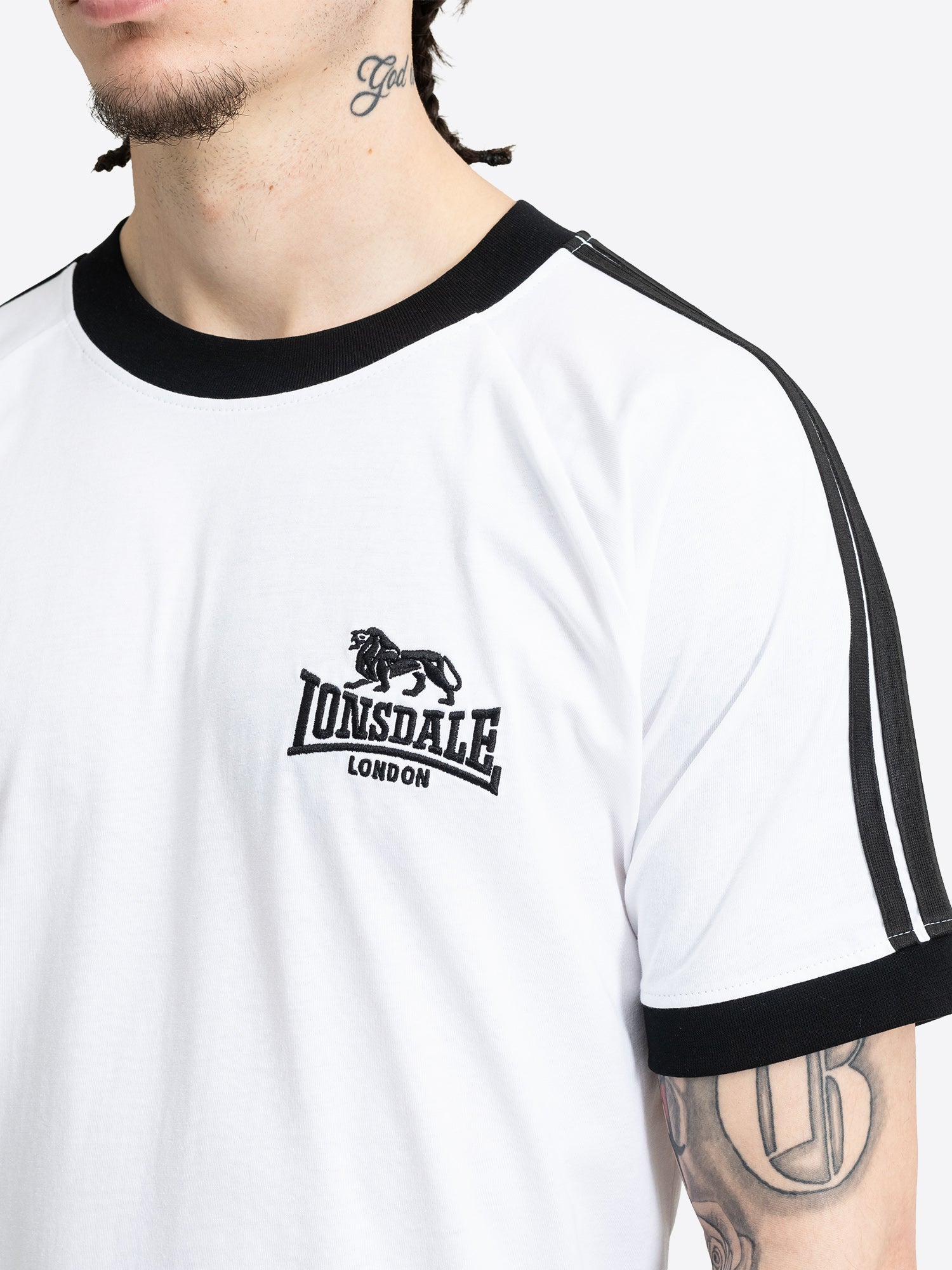 Nahaufnahme der kleinen Lonsdale Logo-Stickerei auf der Brust des weissen Baumwoll-Shirts.