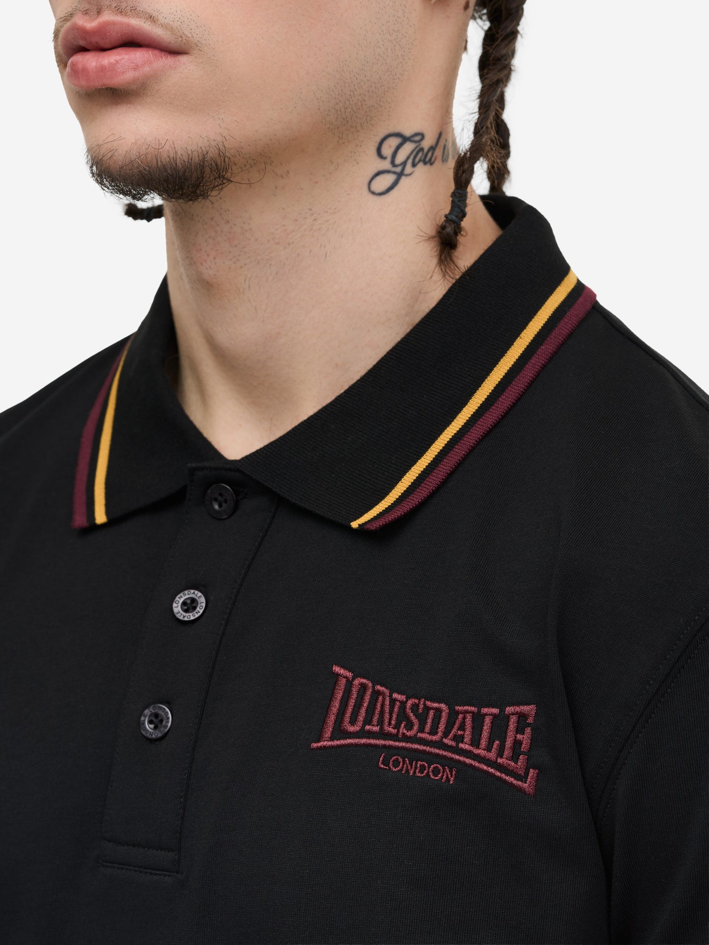 Schwarzes Lonsdale Poloshirt aus Piqué mit Stickerei und rot-weissen Kontraststreifen an Kragen und Ärmeln.