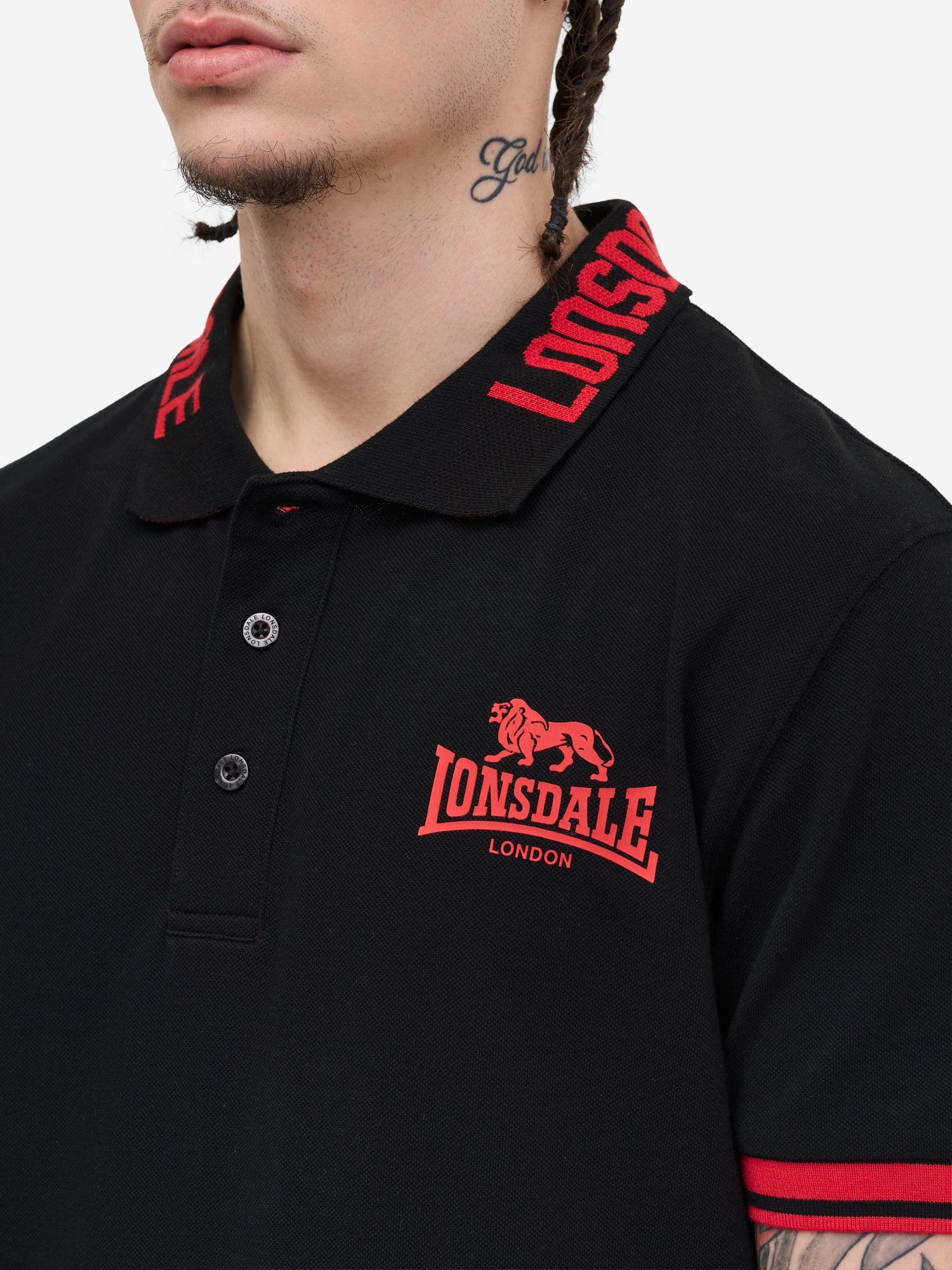 Schwarzes Poloshirt-Kragen mit Lonsdale Markenschriftzug, gestreifte Ärmelbündchen und Union Jack Label an der Seitennaht.