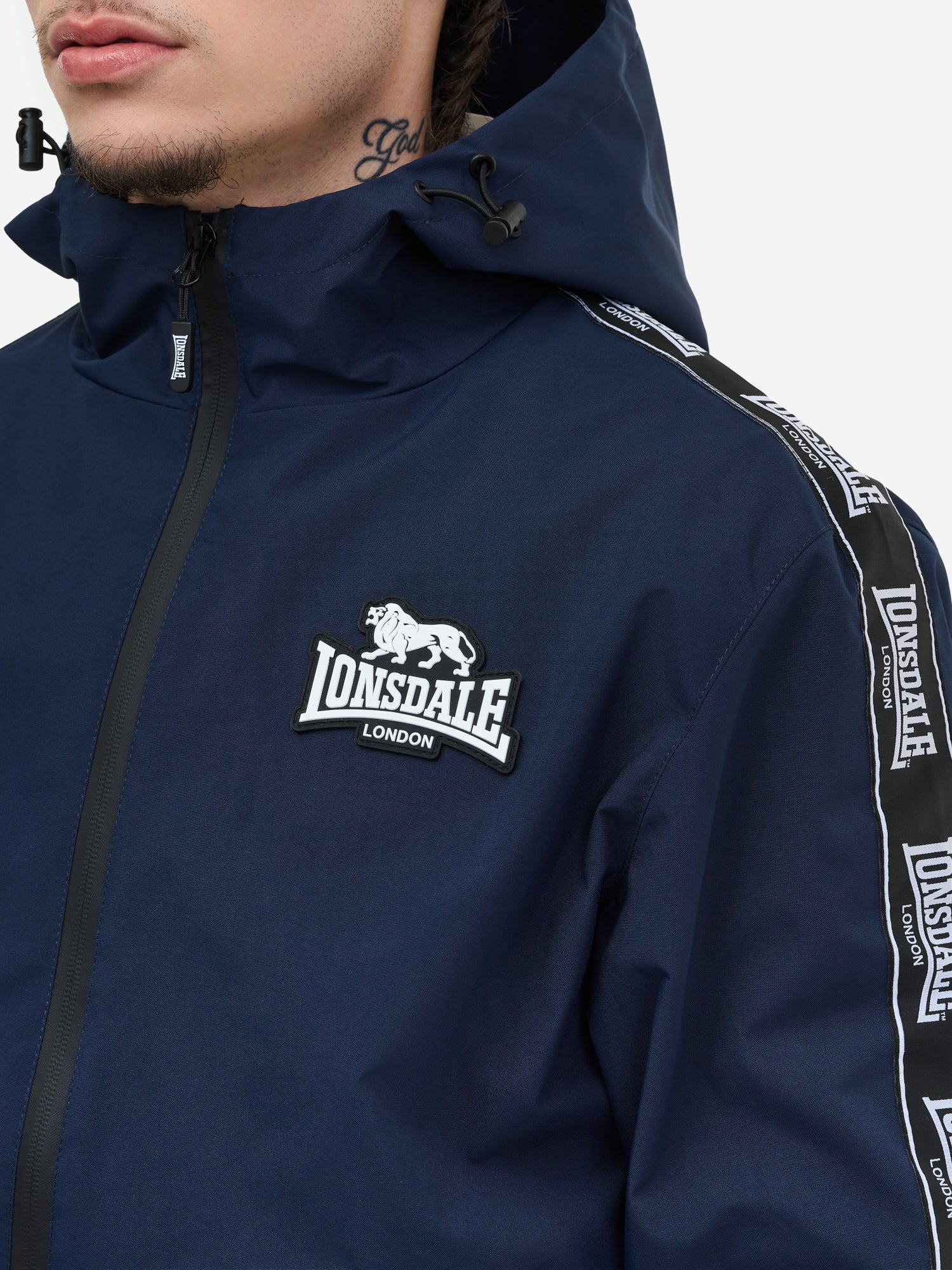 Lonsdale Jacke Detail: Gewebte Logo-Tapes an den Ärmeln, Reissverschlusstaschen und atmungsaktives Mesh-Futter.
