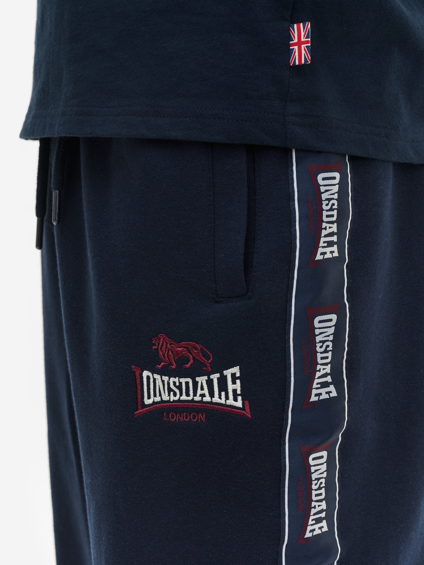 Nahaufnahme der Lonsdale Jogginghose: Fokus auf seitliche Logo-Tapes, die feine Stickerei und elastische Rippbündchen.