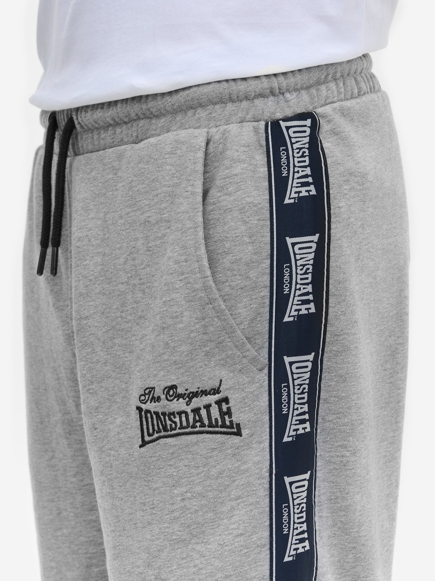 Detail der grauen Lonsdale Jogginghose: Fokus auf Logo-Patch, Stickerei am Oberschenkel und seitliches Logo-Tape.