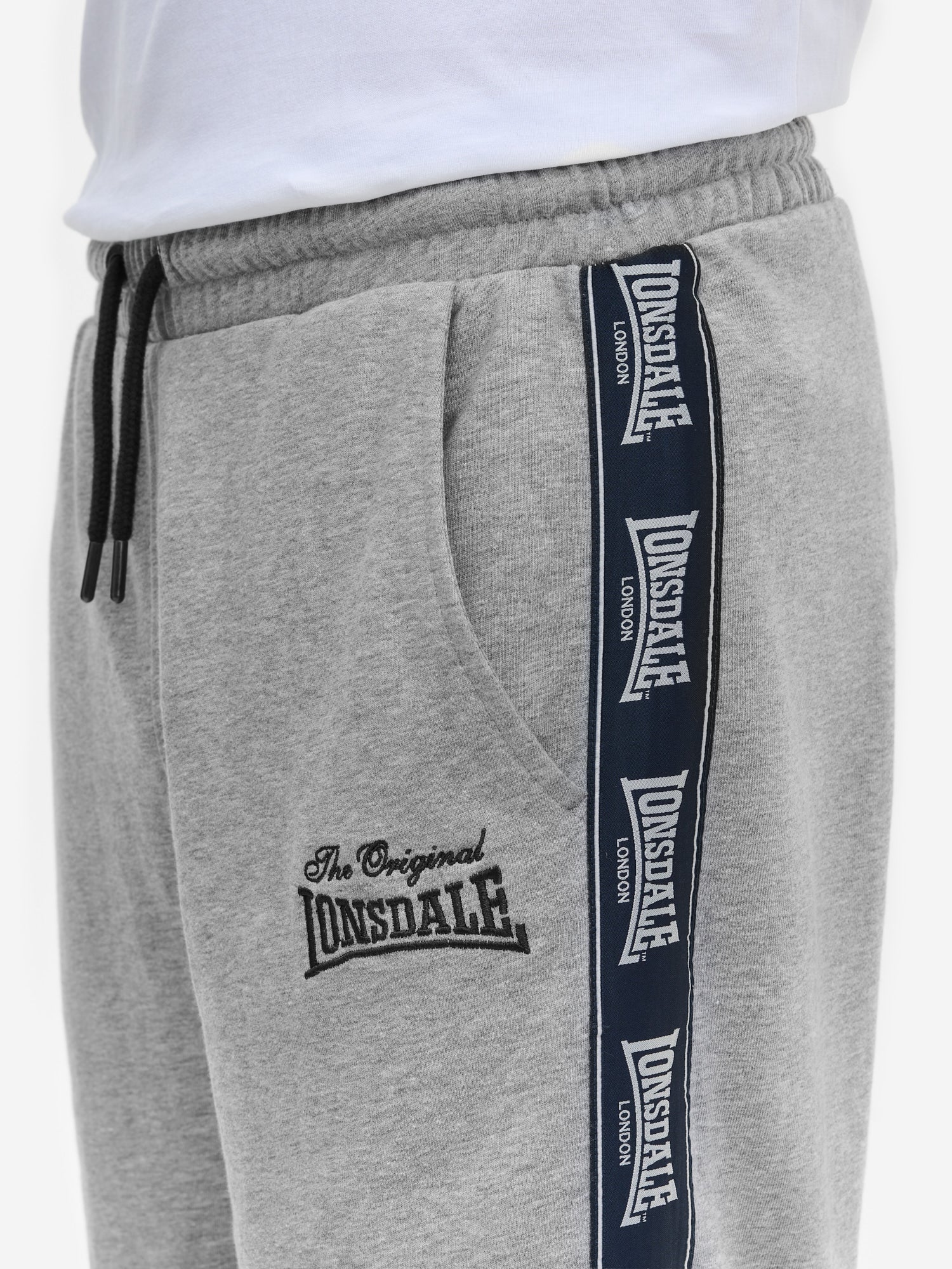 Detail der grauen Lonsdale Jogginghose: Fokus auf Logo-Patch, Stickerei am Oberschenkel und seitliches Logo-Tape.
