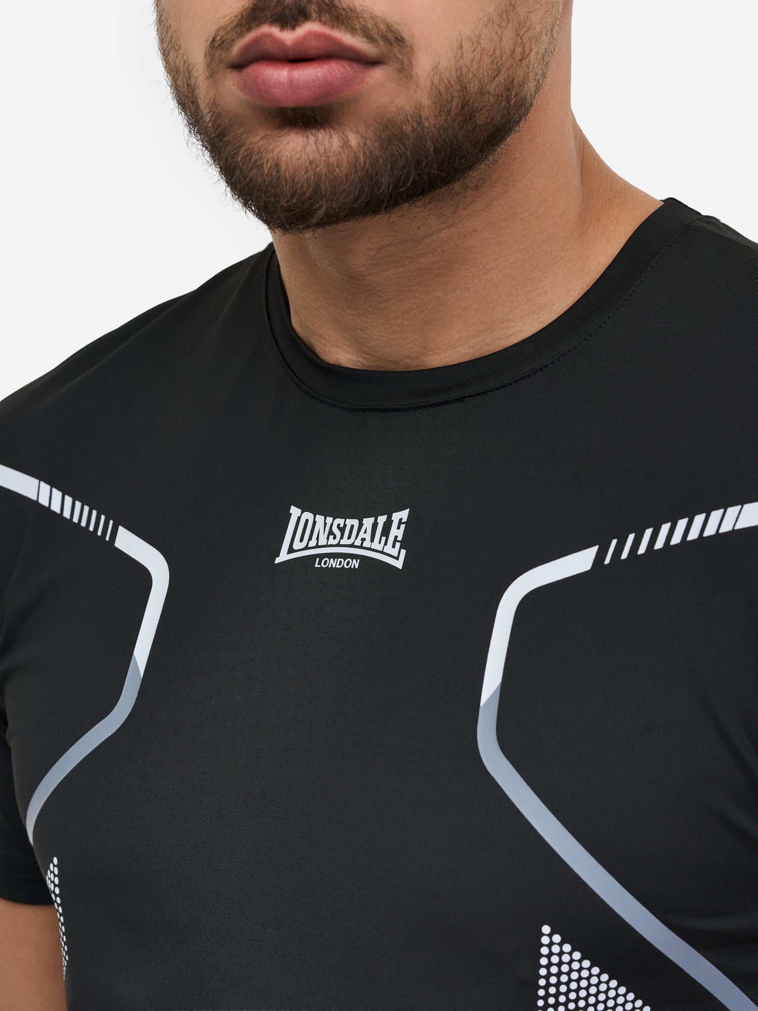 Nahaufnahme Lonsdale Logo und Materialstruktur des schwarzen Funktionsshirts aus 100% Polyester.