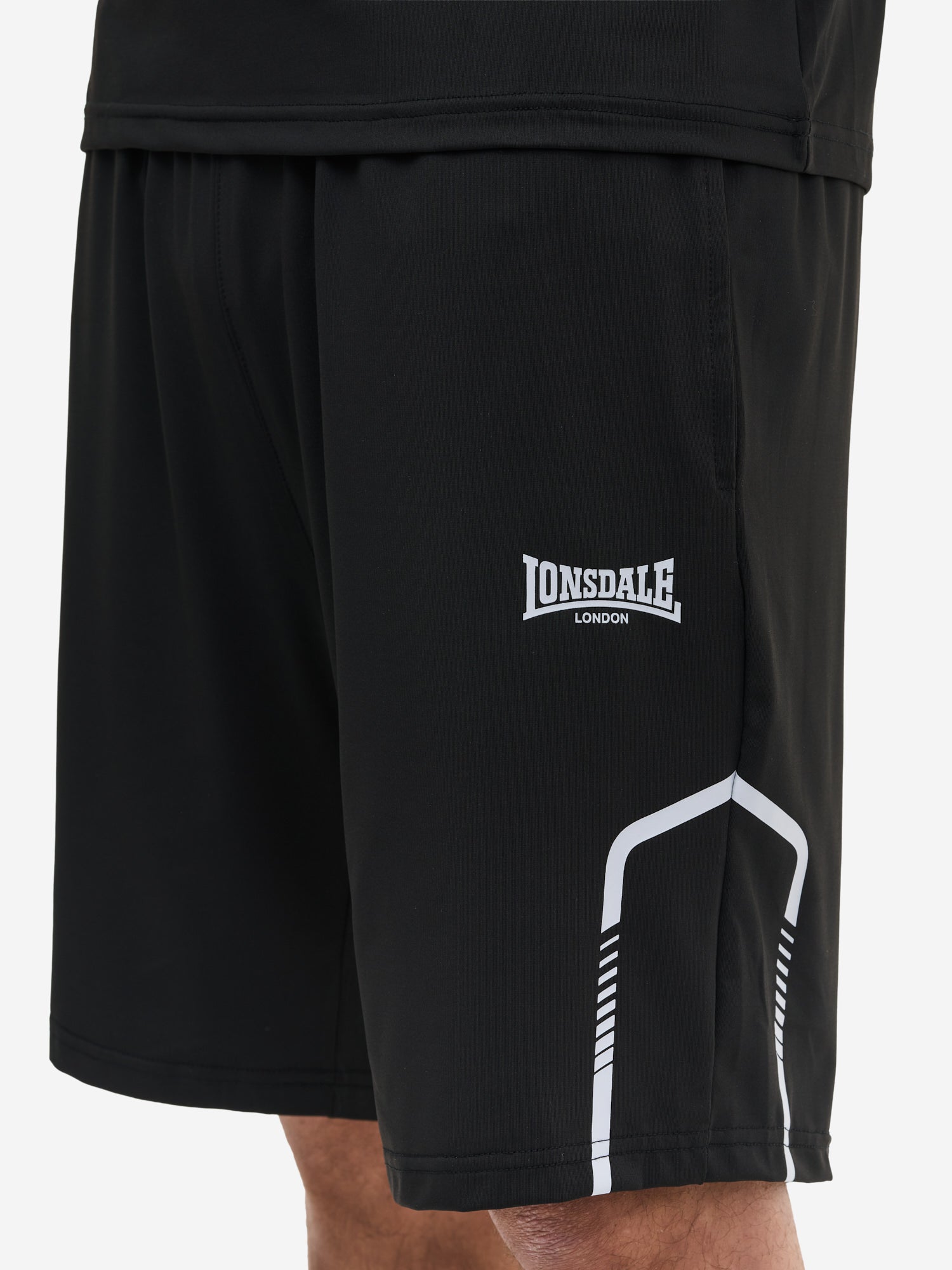 Nahaufnahme Lonsdale Logo und Materialstruktur des schwarzen Funktionsshorts aus 100% Polyester.