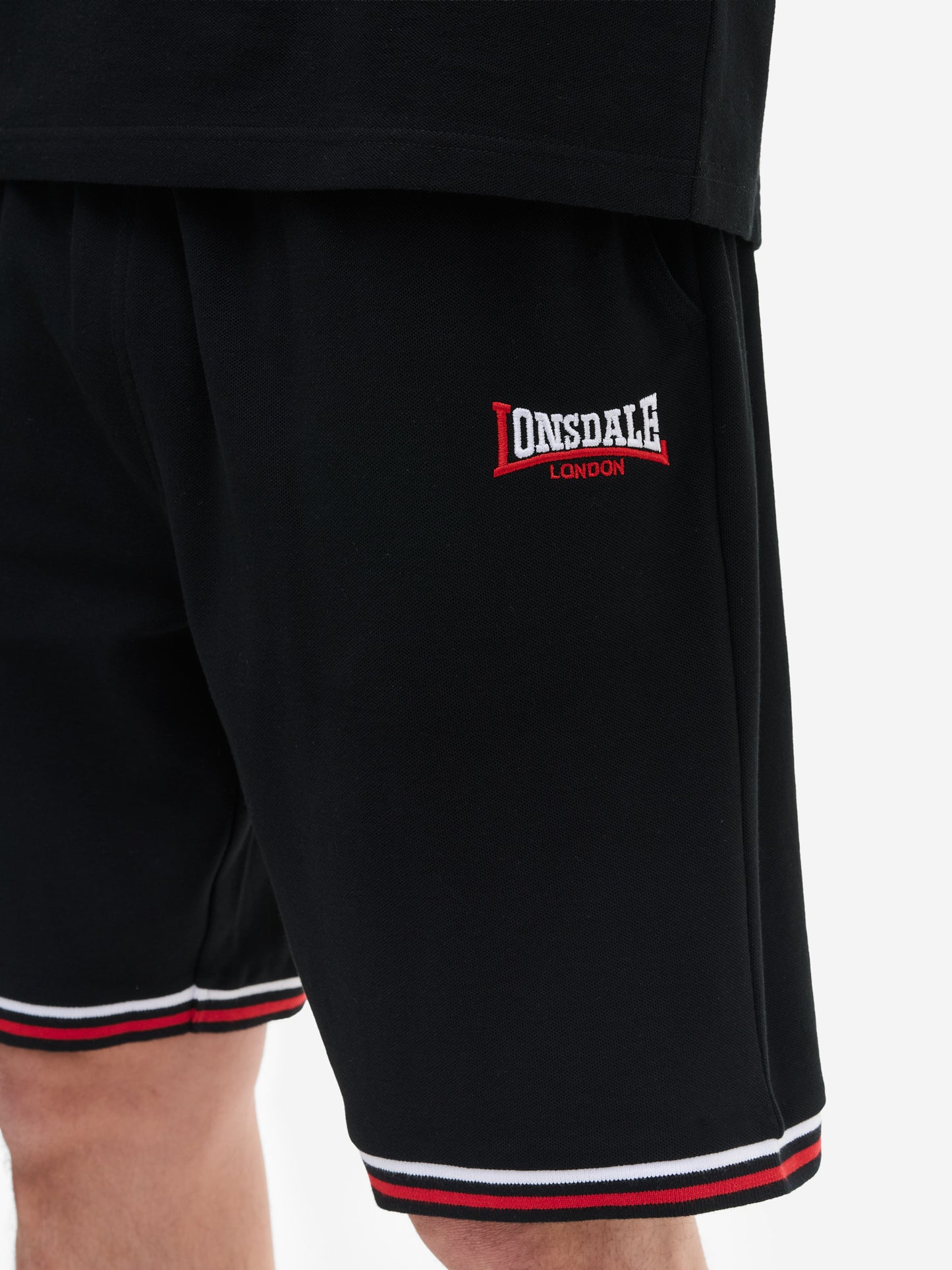Nahaufnahme der Lonsdale Logo-Stickerei und Piqué-Stoffstruktur auf dem schwarzen Shorts