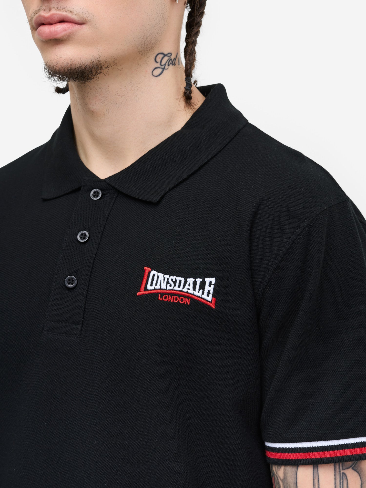 Nahaufnahme der Lonsdale Logo-Stickerei und Piqué-Stoffstruktur auf dem schwarzen Poloshirt