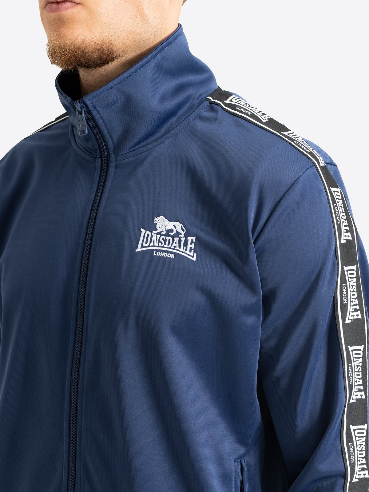 Detailansicht der Lonsdale Trainingsjacke in Navy mit Logo-Stickerei und Ärmelband.