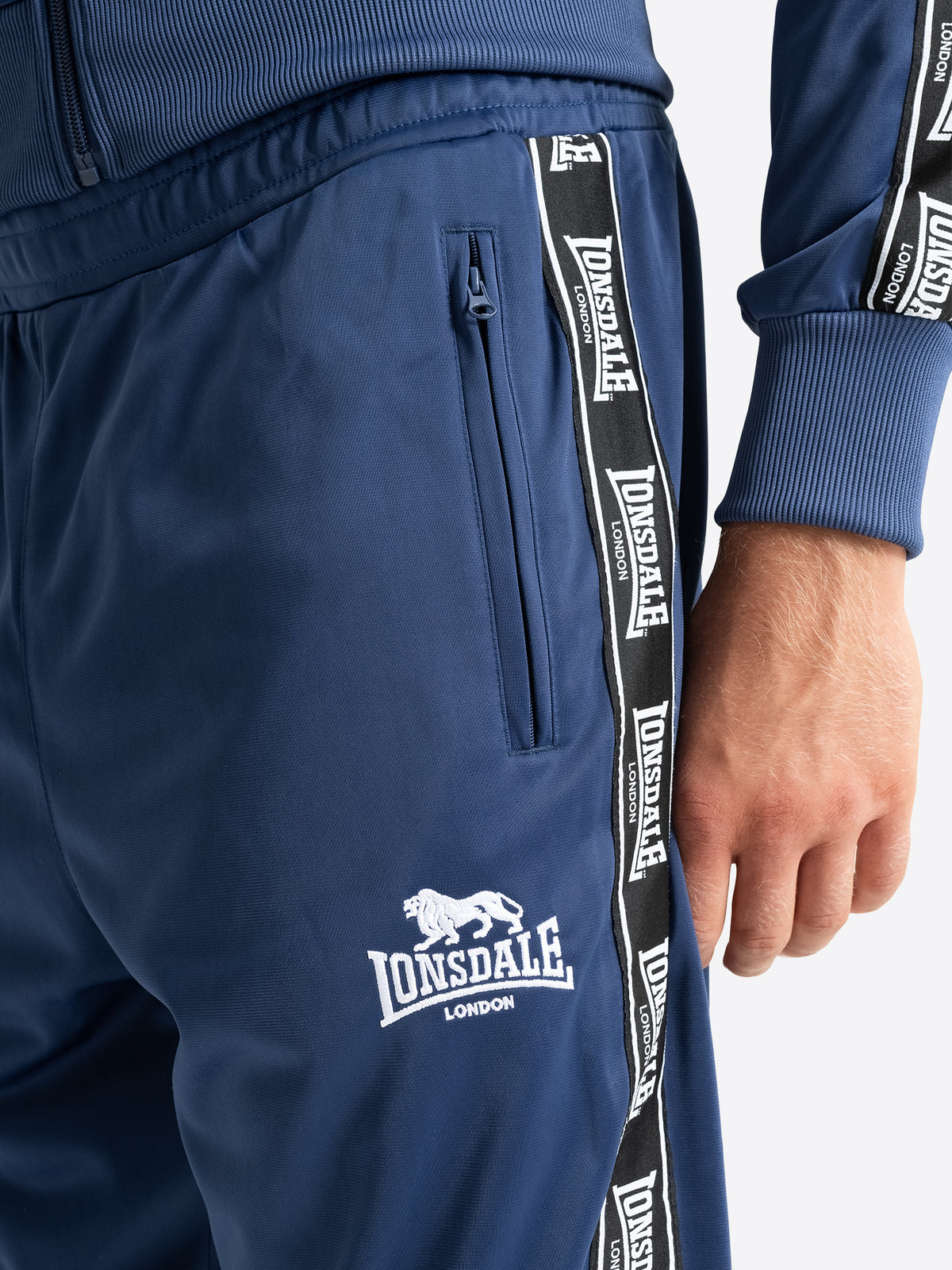 Detailansicht der Lonsdale Jogginghose in Navy mit Reissverschlusstasche und Logo.