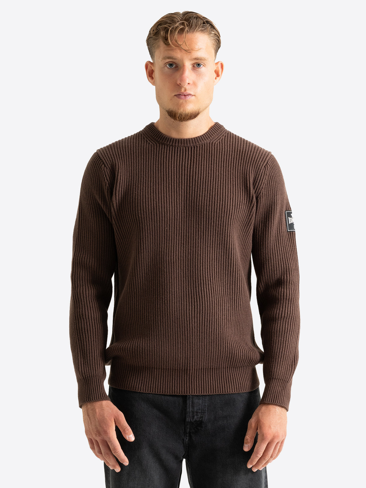 Brauner Herren-Strickpullover in Regular Fit mit Rundhalsausschnitt und 3D-Gummidruck-Patch am linken Ärmel.