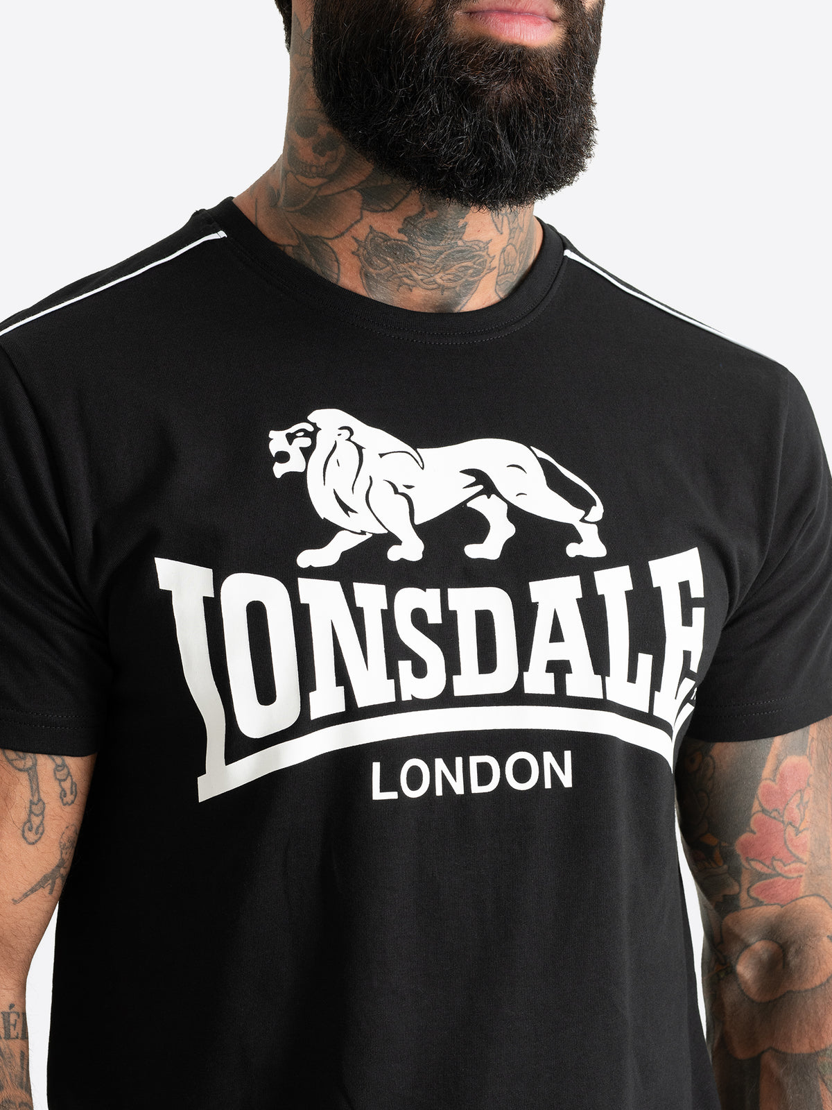 Nahaufnahme des grossen weissen Lonsdale London Logo-Drucks mit Löwen-Motiv auf der Brust des schwarzen Herren T-Shirts.