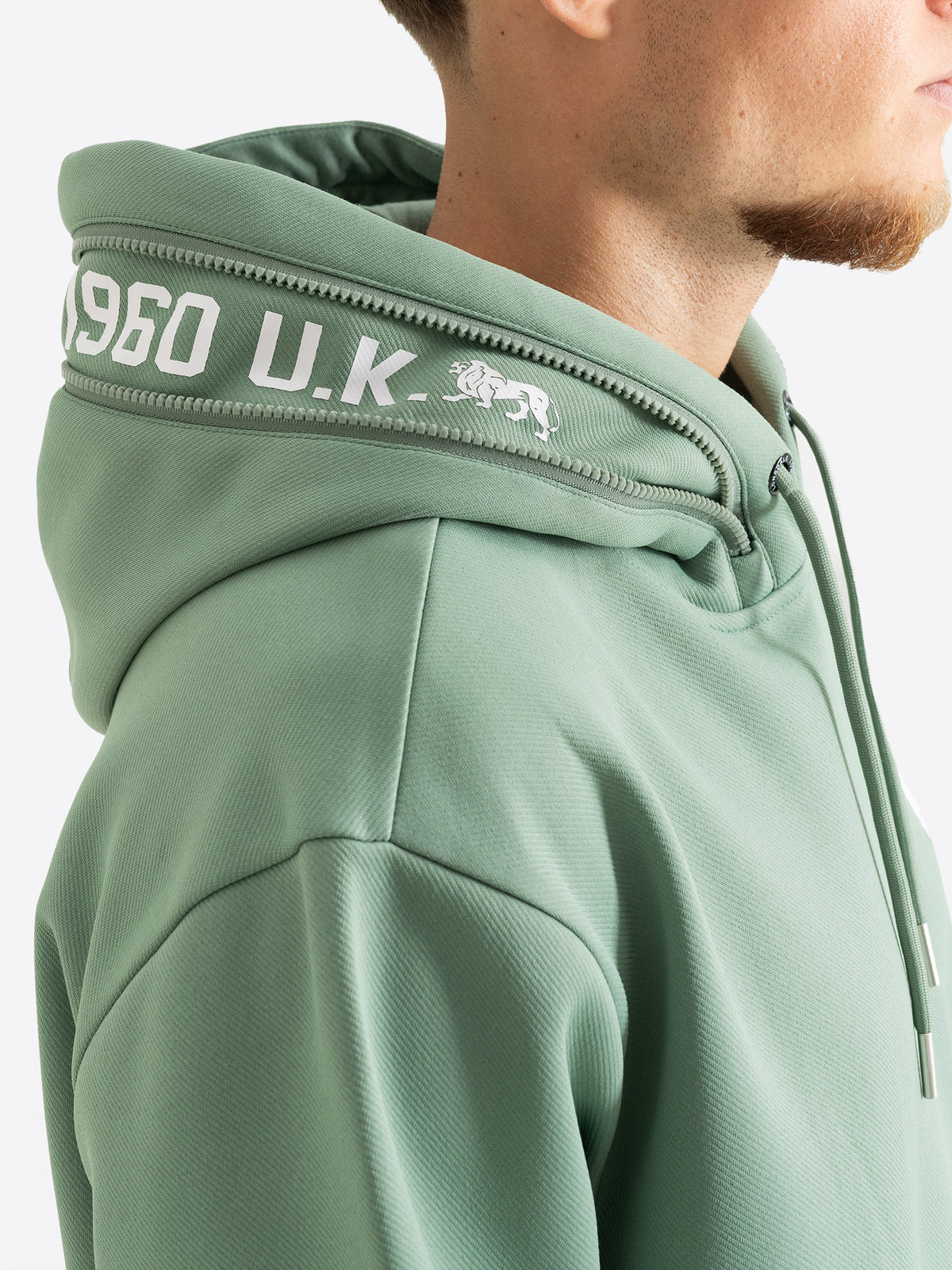 Nahaufnahme vom Lonsdale Kapuzenpullover in Grün mit Schriftzug am Reissverschluss.