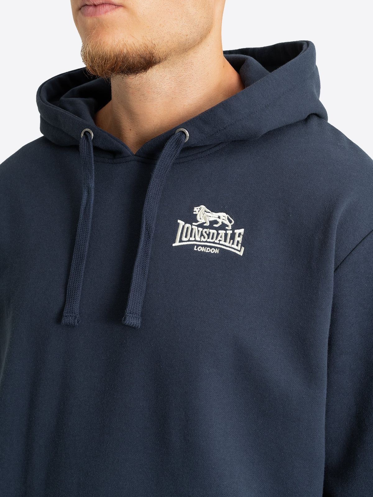 Nahaufnahme des Lonsdale-Logosticks auf der Brust des dunkelblauen Hoodies.
