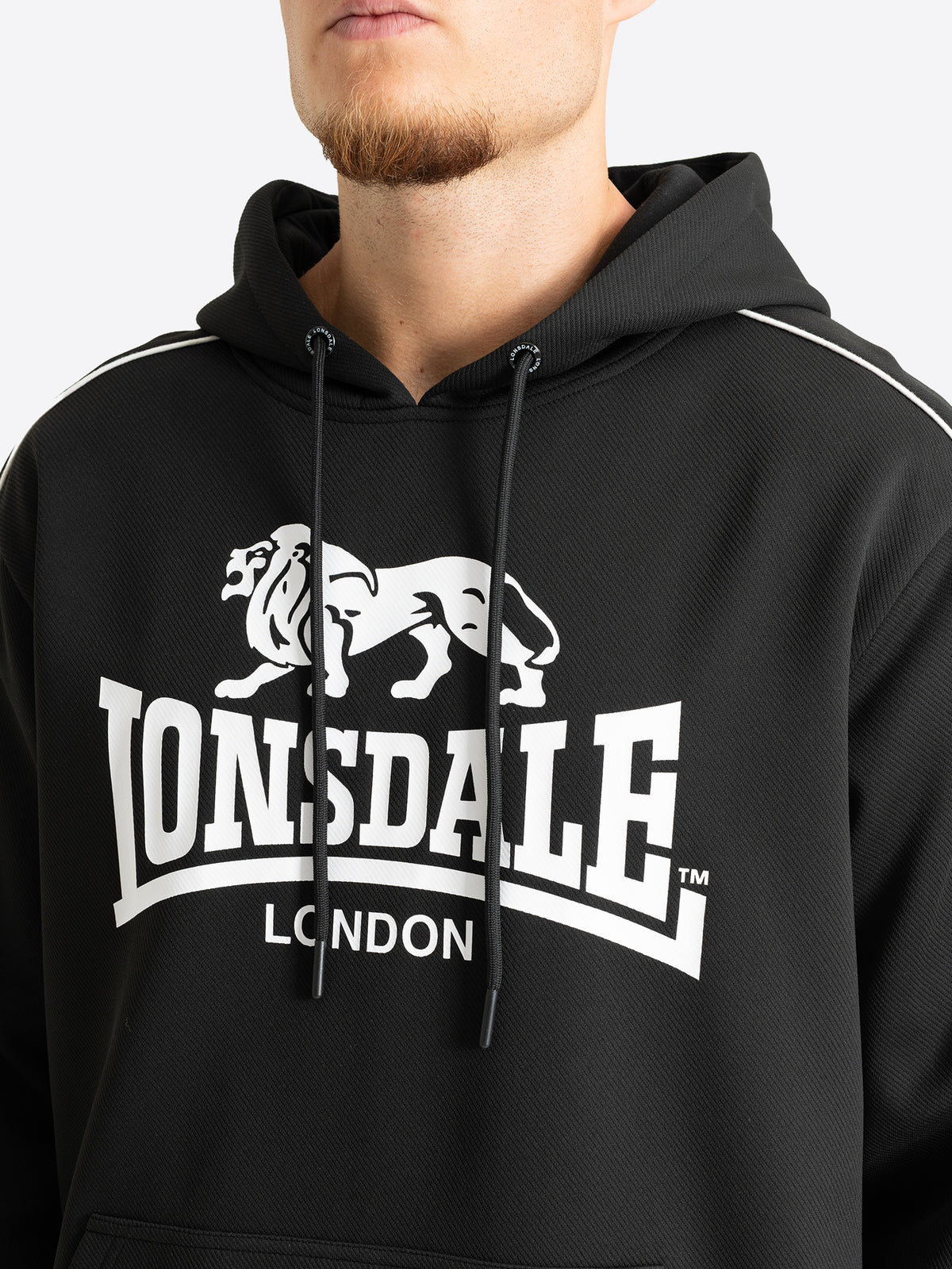 Nahaufnahme des grossen weissen Lonsdale Logo-Drucks auf dem schwarzen Herren-Hoodie.