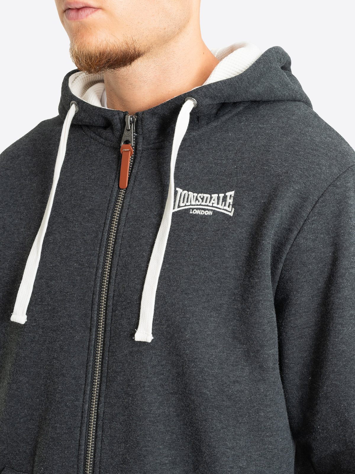 Nahaufnahme des Lonsdale-Logosticks auf der Brust der anthrazitfarbenen Sweatjacke.