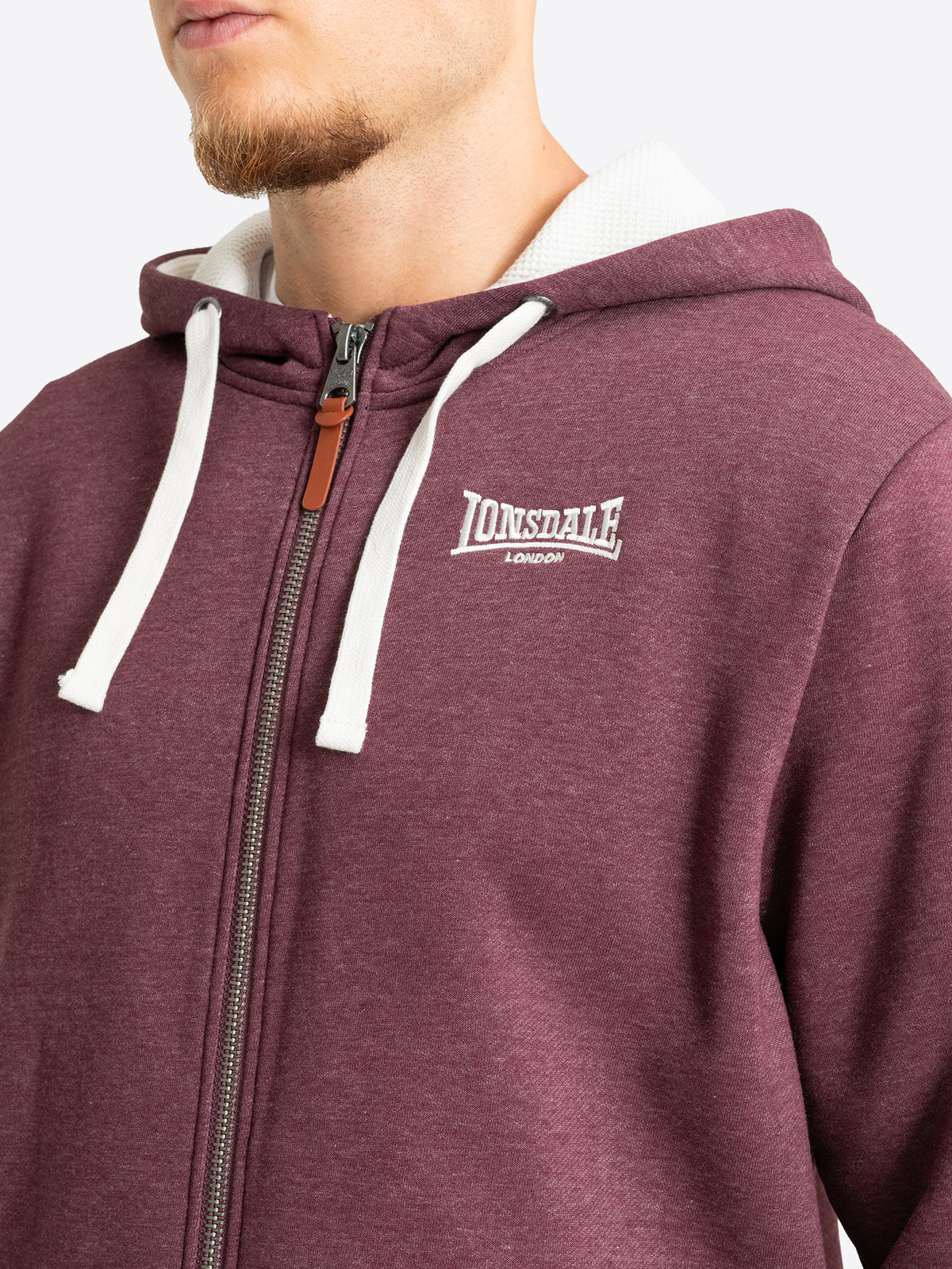 Nahaufnahme des Lonsdale-Logosticks auf der Brust der weinroten Sweatjacke.