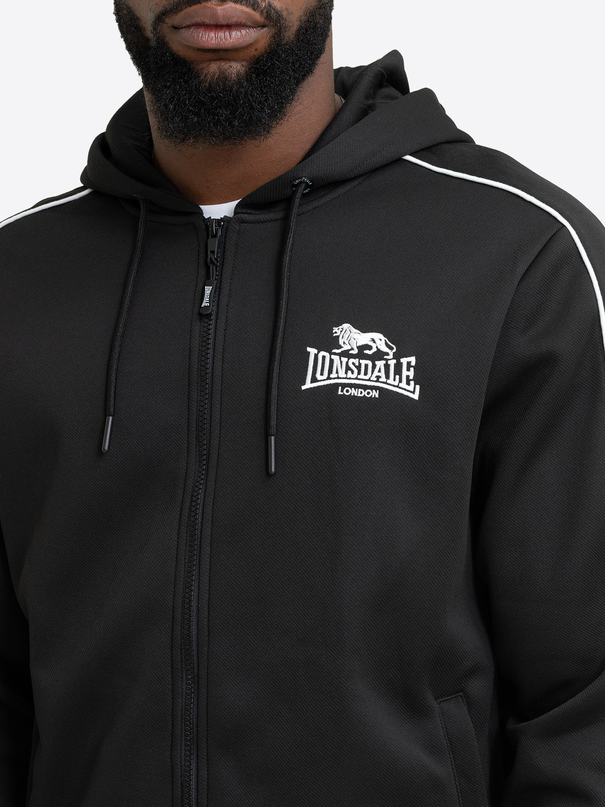 Detailansicht der schwarzen Lonsdale Herren-Sweatjacke mit Fokus auf die weisse Logo-Stickerei und den Reissverschluss.
