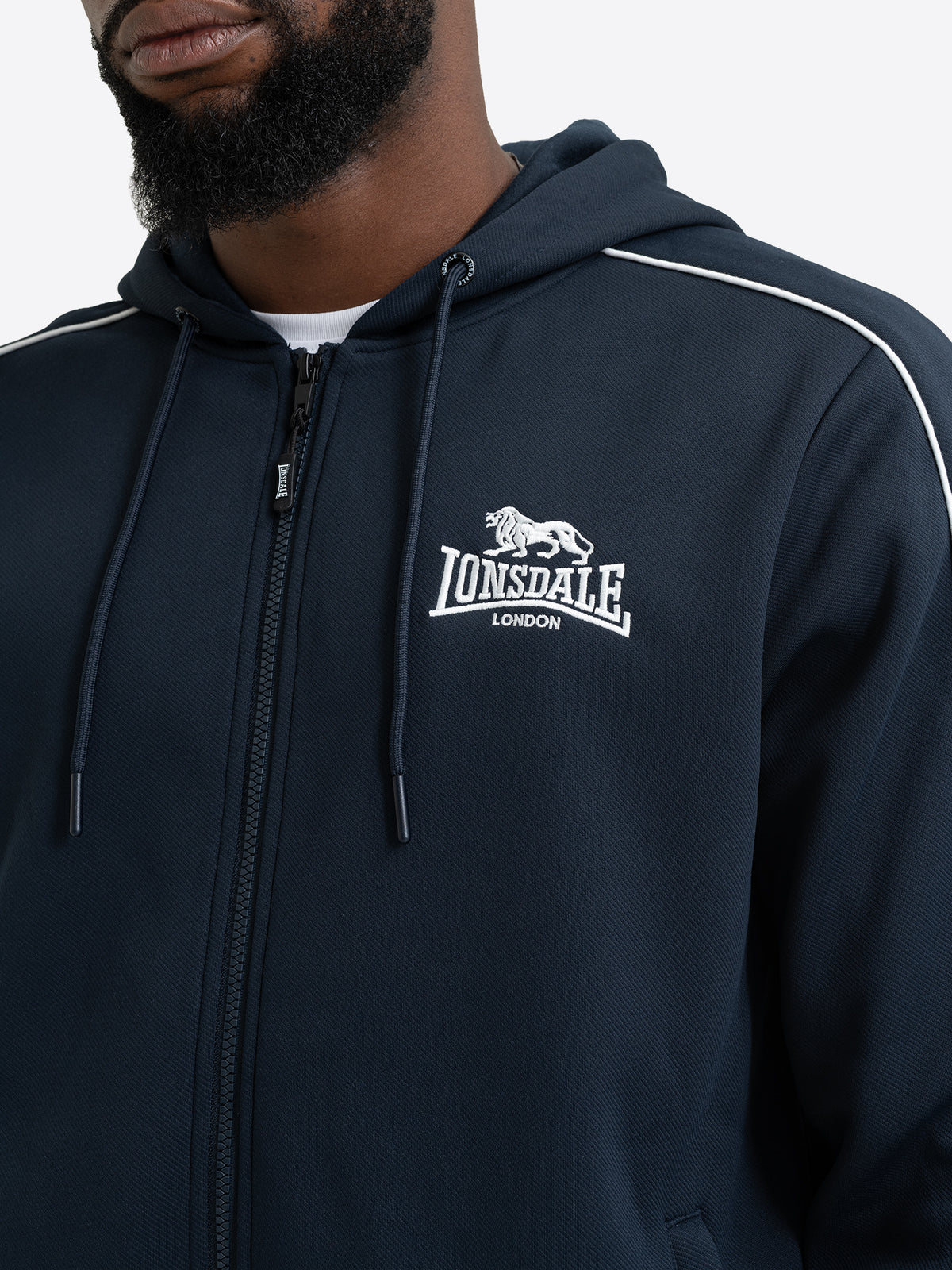 Detailansicht der Lonsdale Herren-Sweatjacke in Dark Navy mit Fokus auf die weisse Logo-Stickerei und den Reissverschluss.