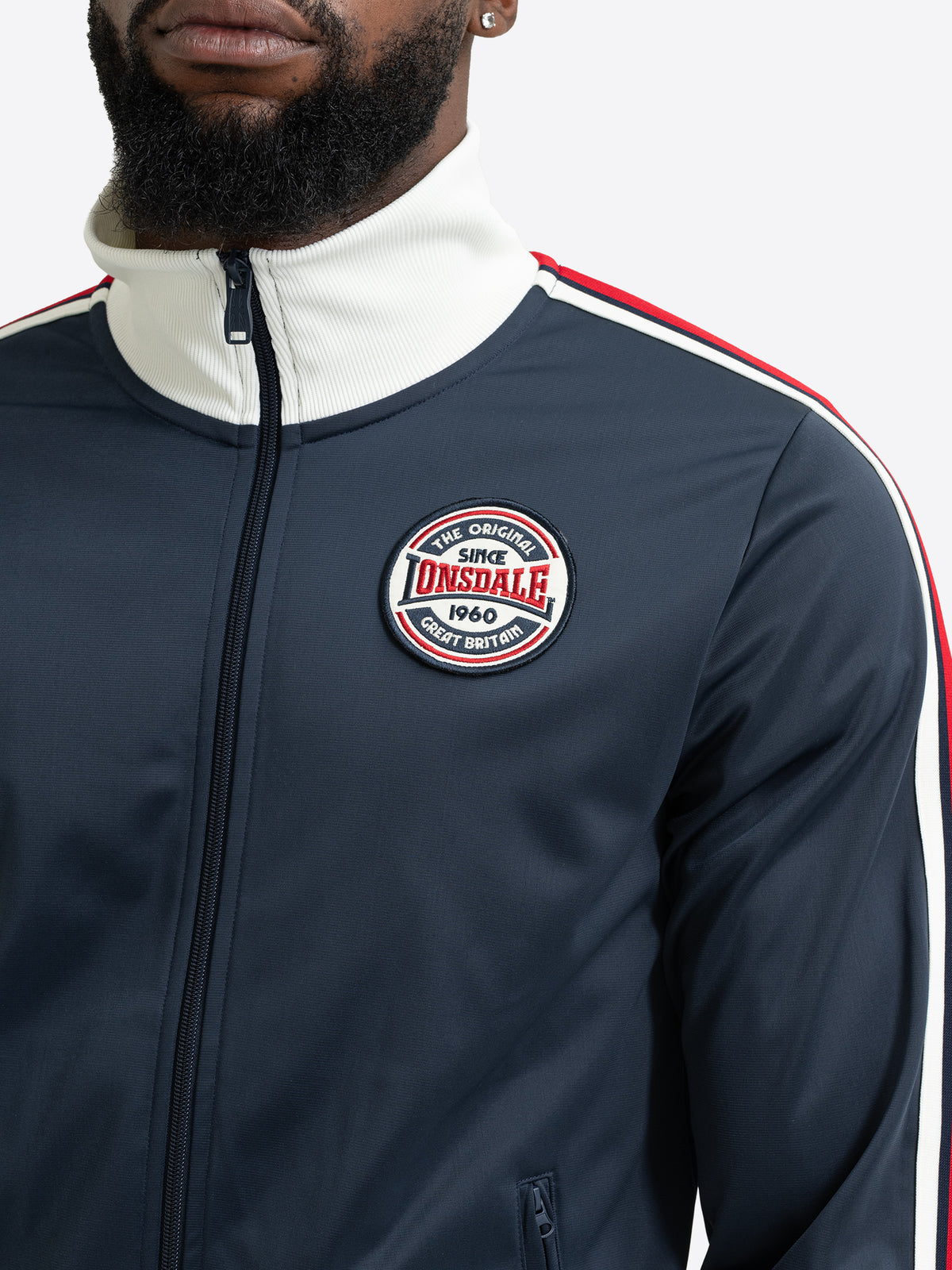 Detailansicht der dunkelblauen Lonsdale Joggingjacke mit rundem Logo-Patch