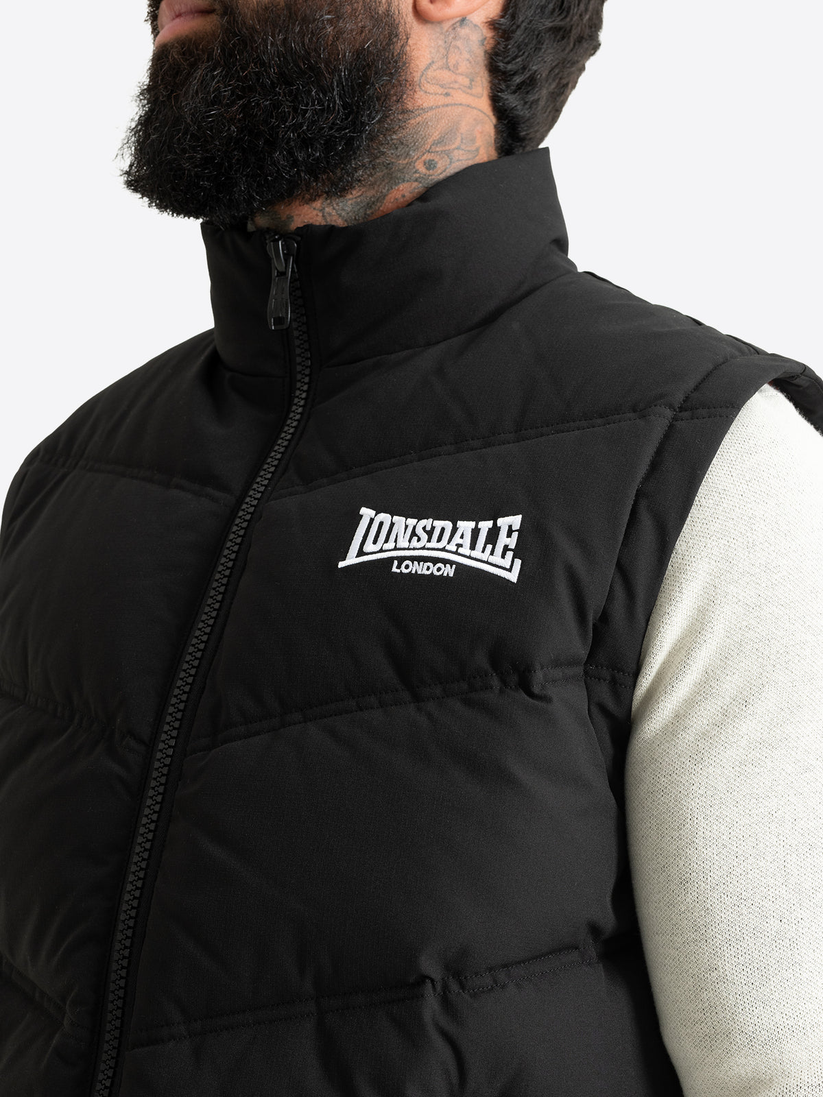 Nahaufnahme der Lonsdale Herren-Steppweste mit hochgeschlossenem Stehkragen und weissem Brust-Logo.