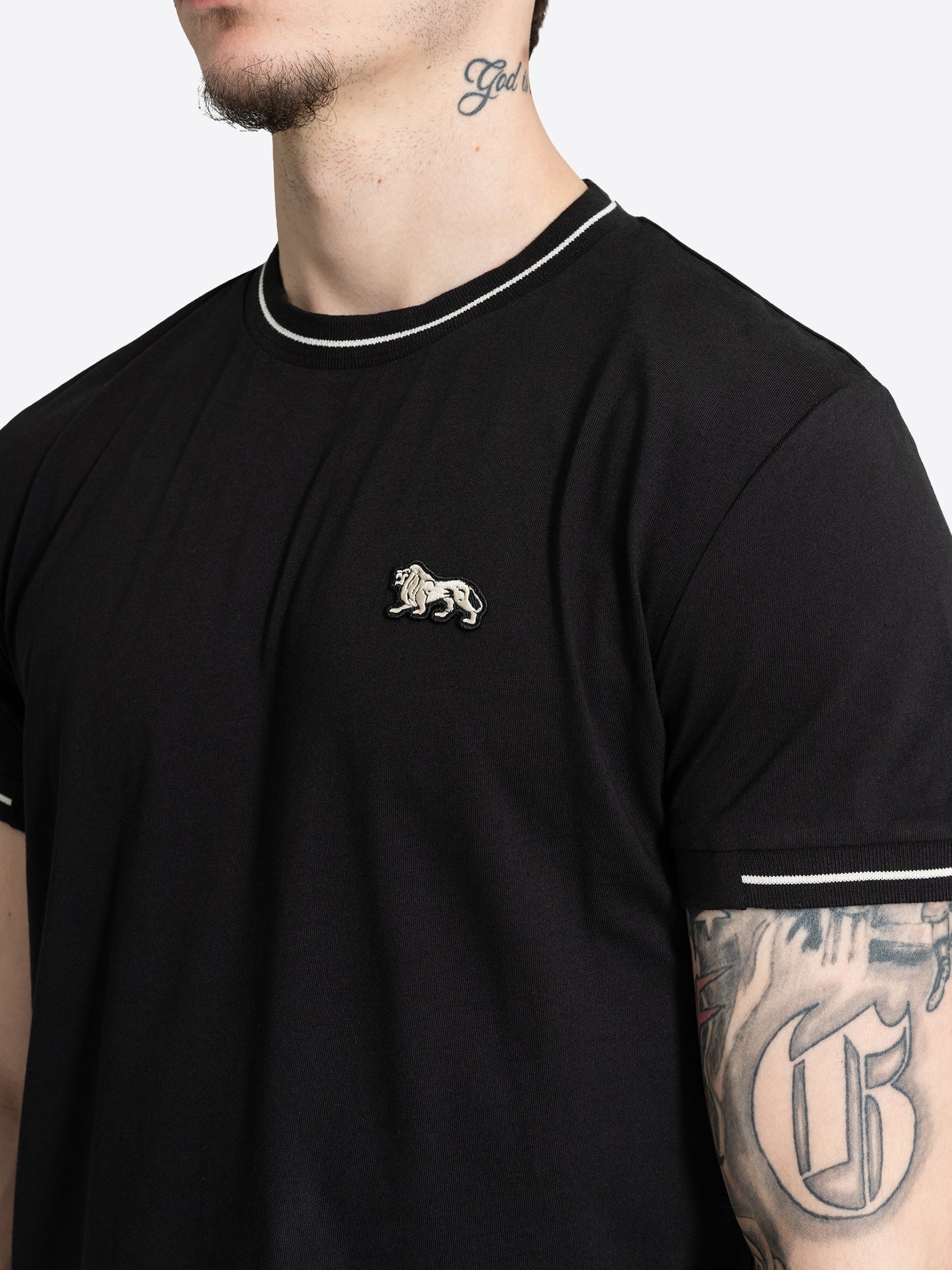 Nahaufnahme des kleinen Löwen-Badges auf der Brust des schwarzen Lonsdale T-Shirts.
