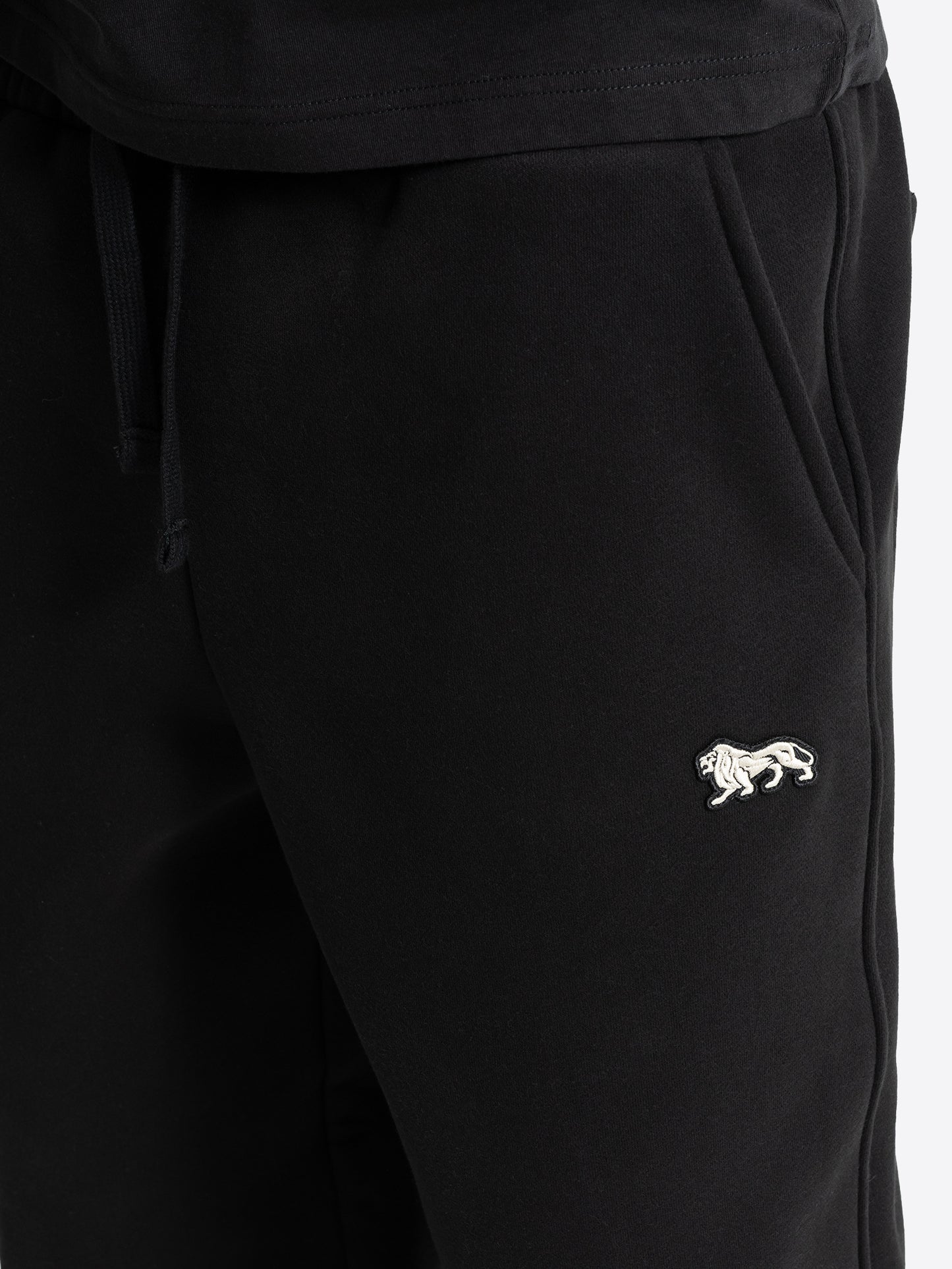 Weisser Lonsdale London Löwen-Badge auf schwarzer Herren-Jogginghose. Schweizer Online-Shop für Streetwear.
