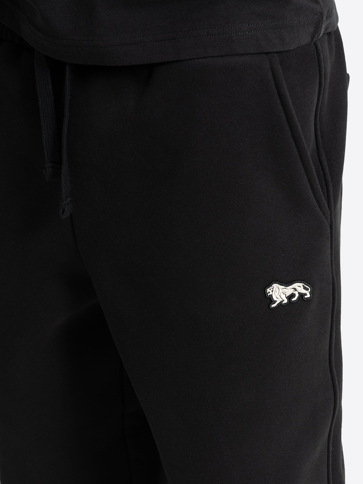 Weisser Lonsdale London Löwen-Badge auf schwarzer Herren-Jogginghose. Schweizer Online-Shop für Streetwear.
