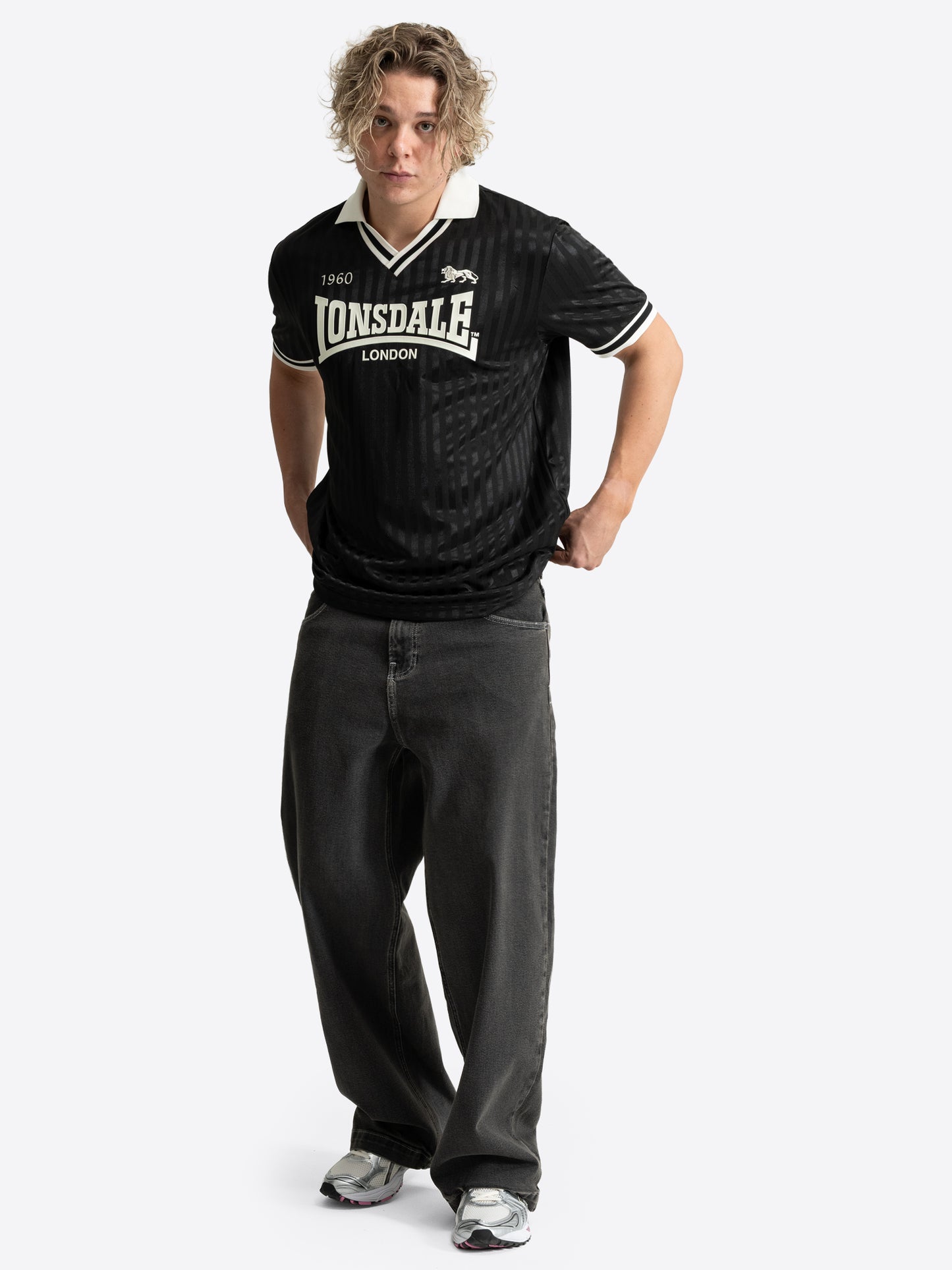 Lonsdale Unisex Trikot in Schwarz mit gestreiftem Jacquard-Muster, weissem V-Ausschnitt und Retro-Logo auf der Brust.