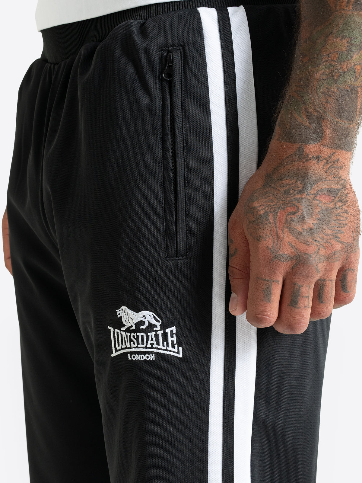 Lonsdale Herren-Trainingshose Schwarz – Detailansicht mit weissem Logo und Reissverschluss-Tasche.