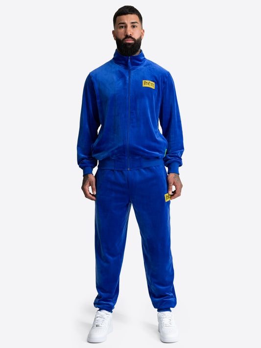 Blauer BENLEE Herren-Jogginganzug aus Velours mit gelbem Logo-Patch auf Jacke und Hose.