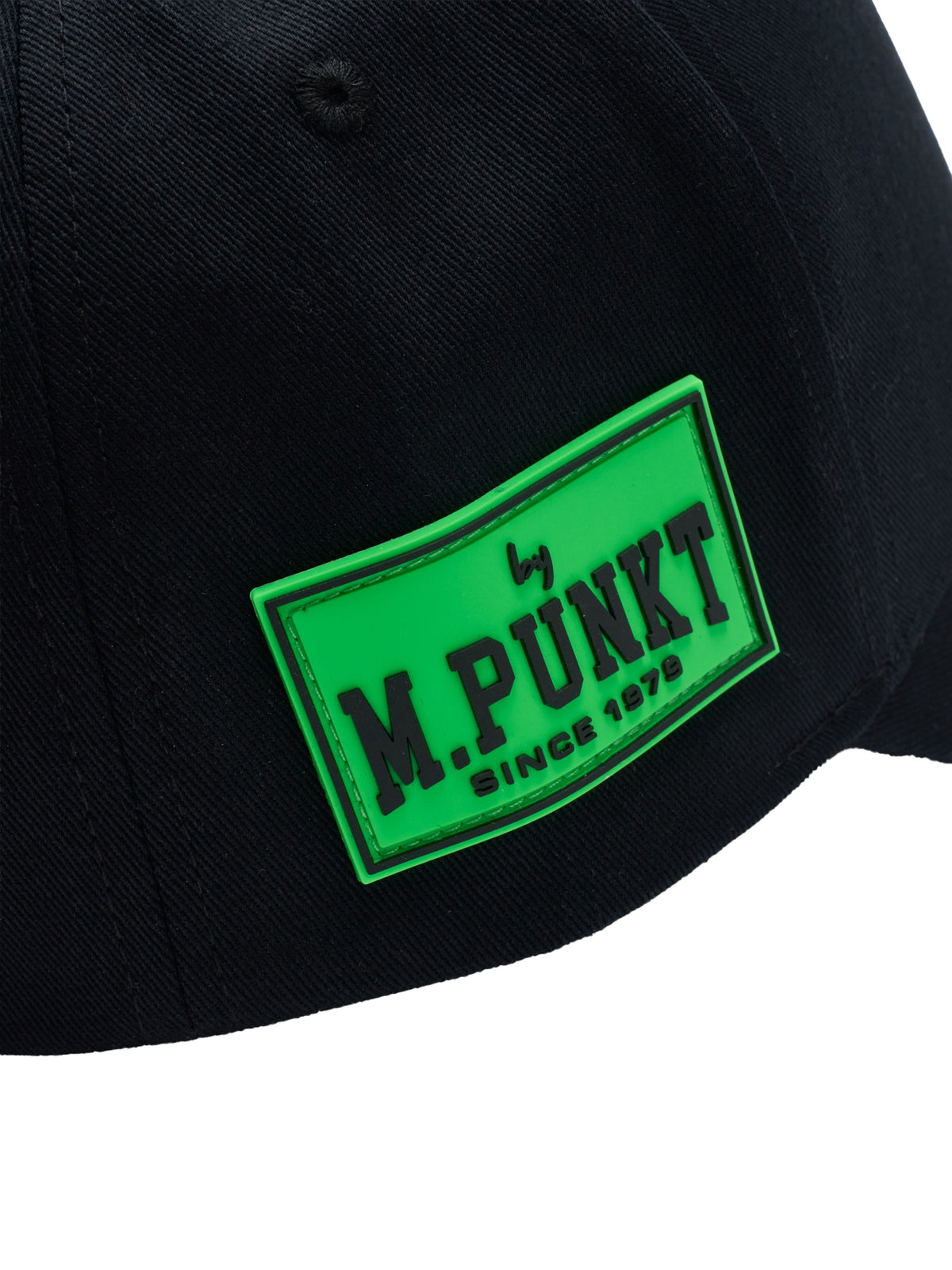 Nahaufnahme eines neongrünen „by M.PUNKT“-Logos auf einer schwarzen Kappe.
