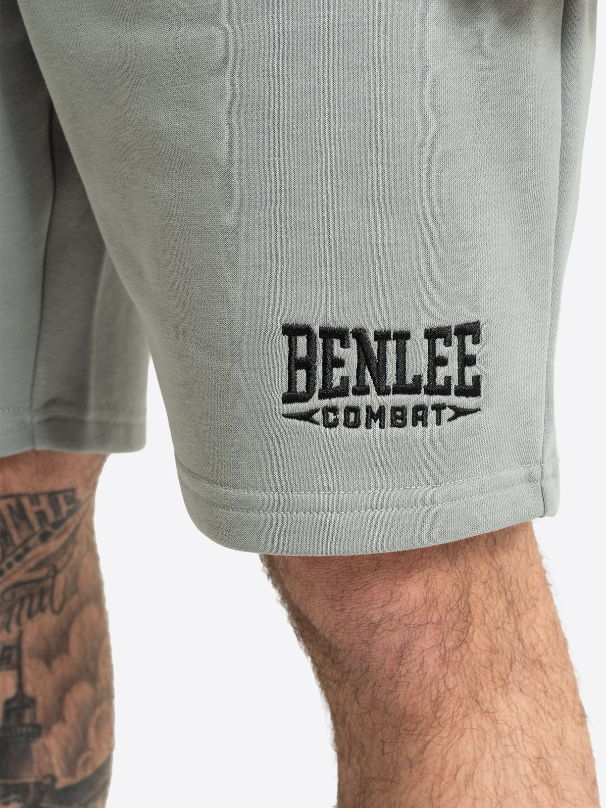 Detailansicht der grauen BENLEE Herren-Shorts mit aufgesticktem schwarzen Logo über dem Hosensaum.
