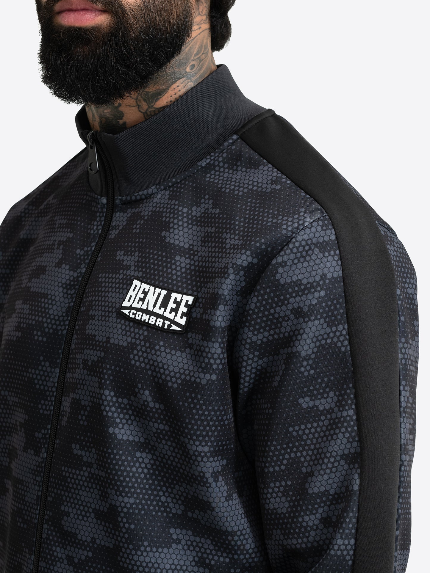 Benlee Trainingsjacke Detail: 3D-Logo-Badge & Interlock-Struktur in Schwarz.
