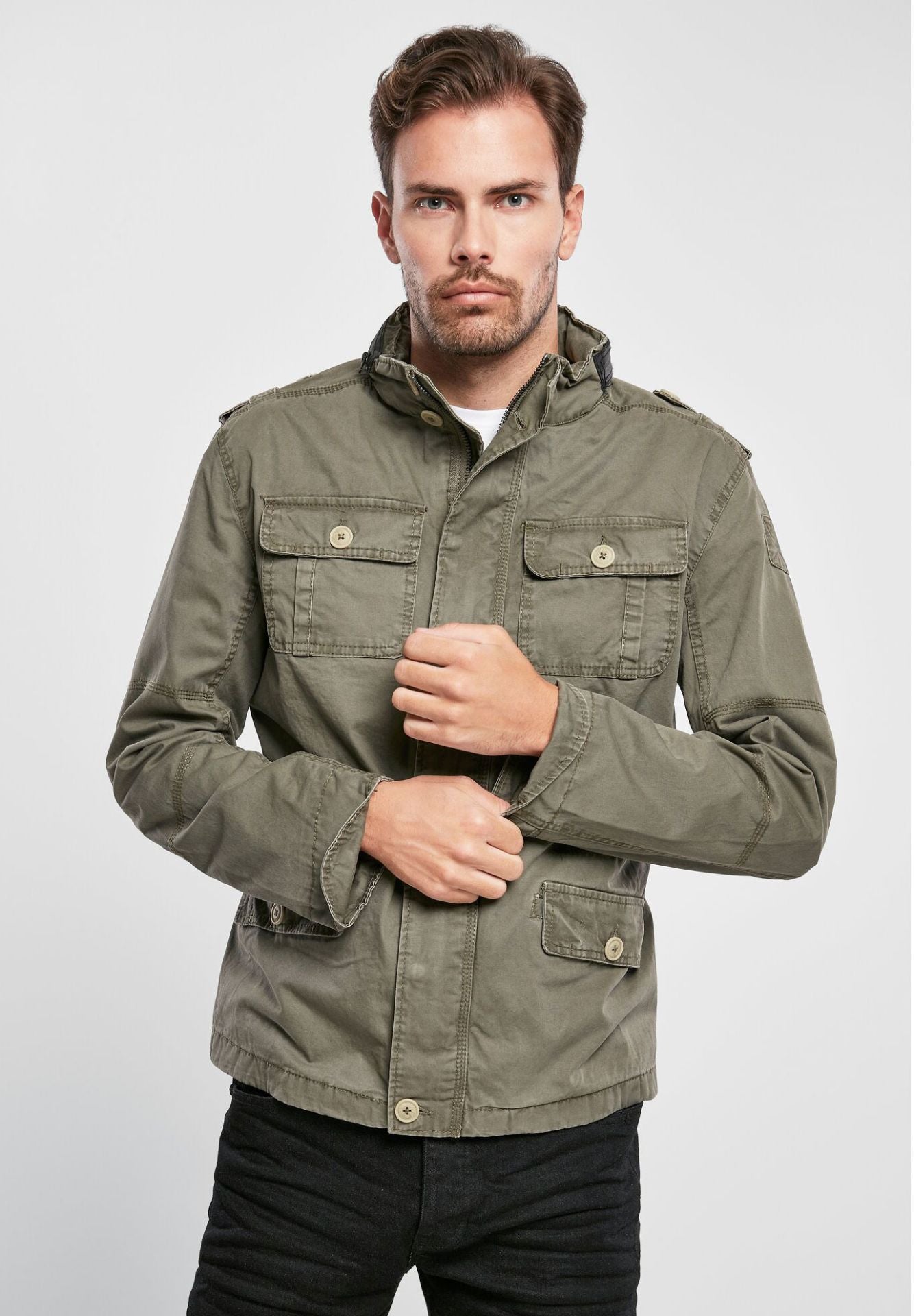 Brandit modifizierte Feldjacke in Oliv mit Logo-Badge, versteckter Kapuze im Kragen, Stehkragen mit Kunstlederapplikation und Used-Effekten.