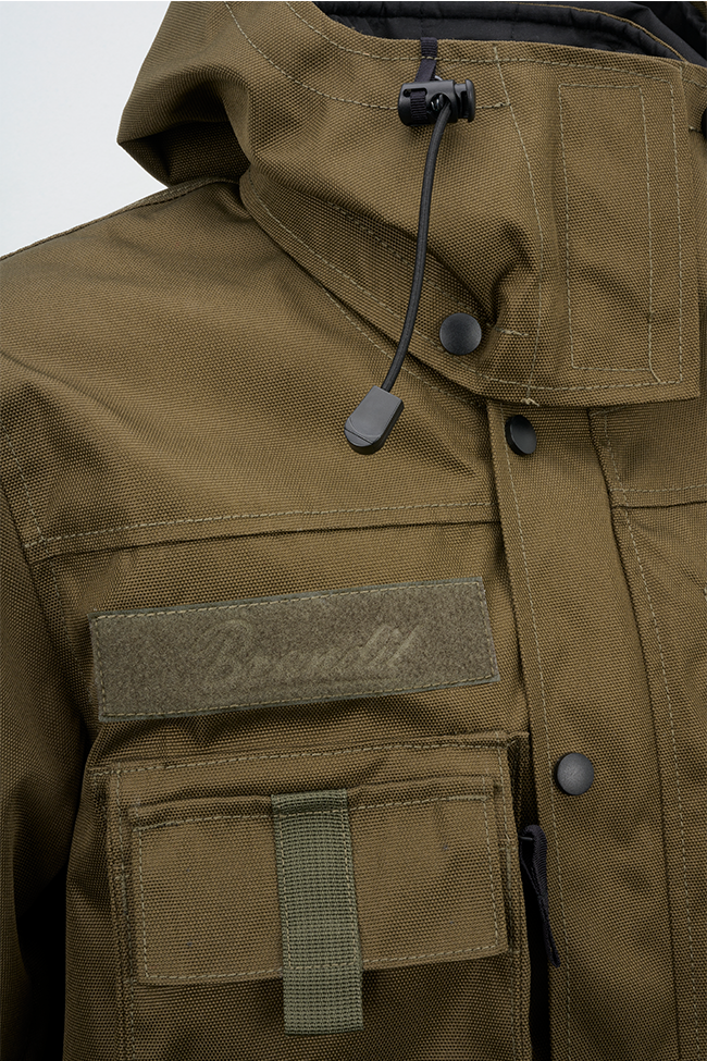 Olivfarbene Brandit taktische Performance-Jacke aus wasserabweisendem Material mit abnehmbarer Kapuze, verstellbarer Taille, Molle-Bändern und vielen Taschen.