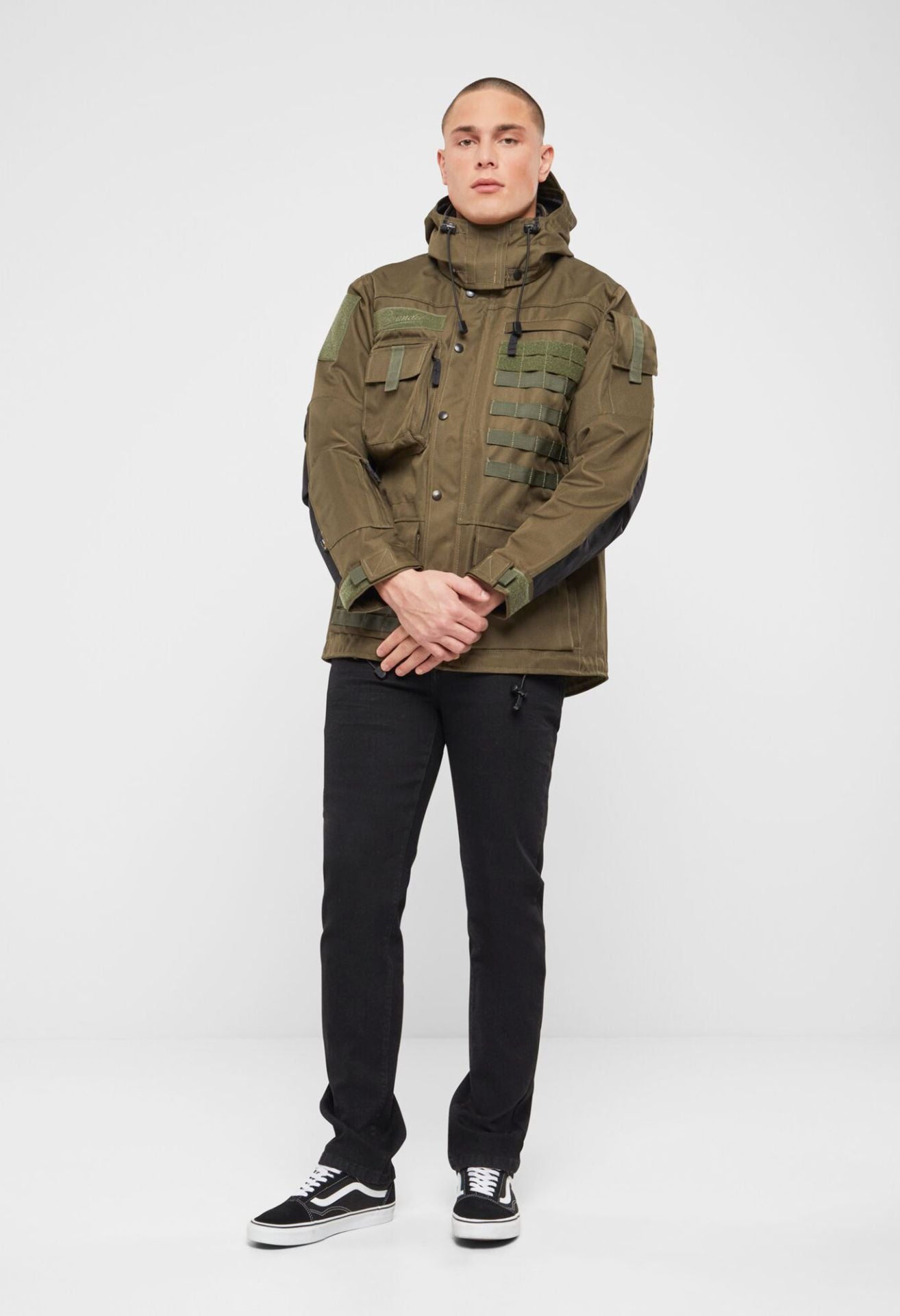 Olivfarbene Brandit taktische Performance-Jacke aus wasserabweisendem Material mit abnehmbarer Kapuze, verstellbarer Taille, Molle-Bändern und vielen Taschen.