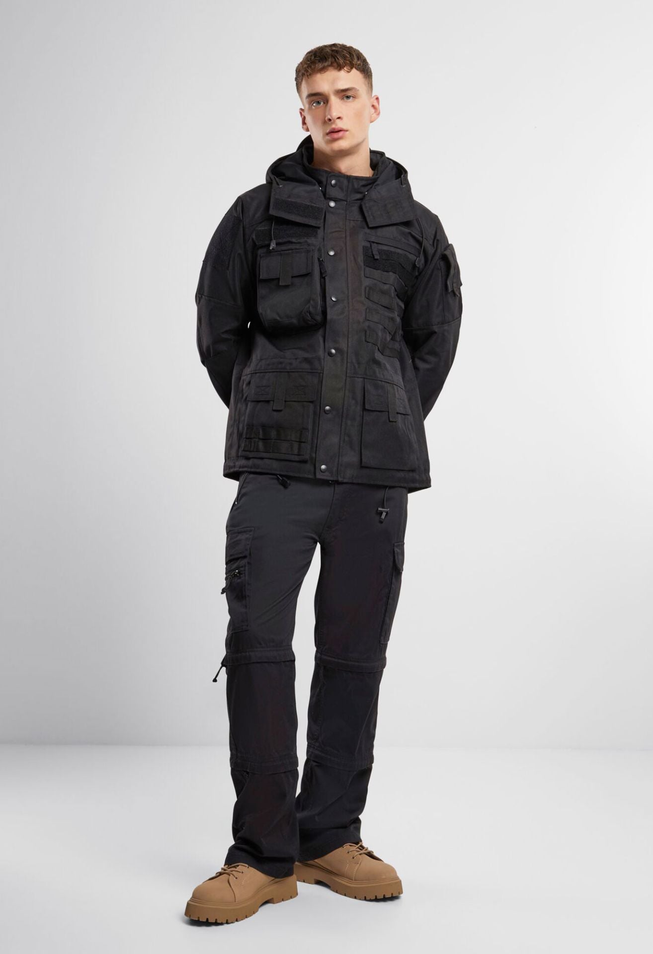 Schwarze Brandit taktische Performance-Jacke aus wasserabweisendem 900D-Polyester mit abnehmbarer Kapuze, verstellbarer Taille und Molle-Bändern