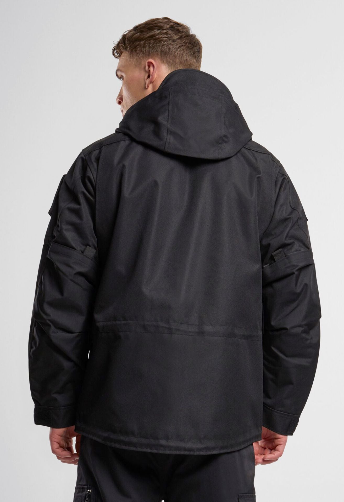 Schwarze Brandit taktische Performance-Jacke aus wasserabweisendem 900D-Polyester mit abnehmbarer Kapuze, verstellbarer Taille und Molle-Bändern