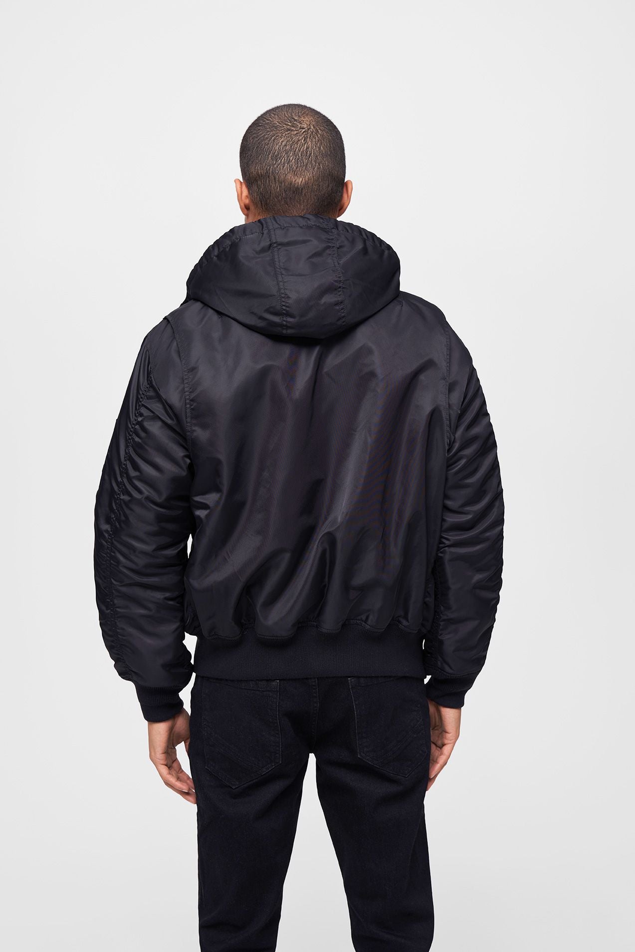 Schwarze Brandit CWU Fliegerjacke mit warmem Teddyfell, gefütterter Kapuze, Strickbündchen und wind-/wasserabweisendem Nylon.