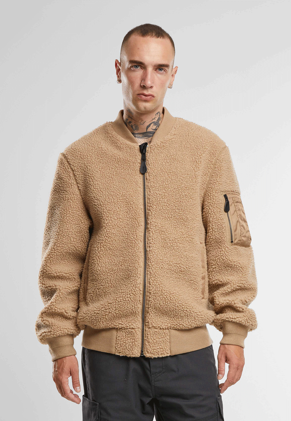 Brandit Teddyfleece-Bomberjacke in Camel mit Strickbund, zwei Einschubtaschen und Oberarmtasche mit Reissverschluss.