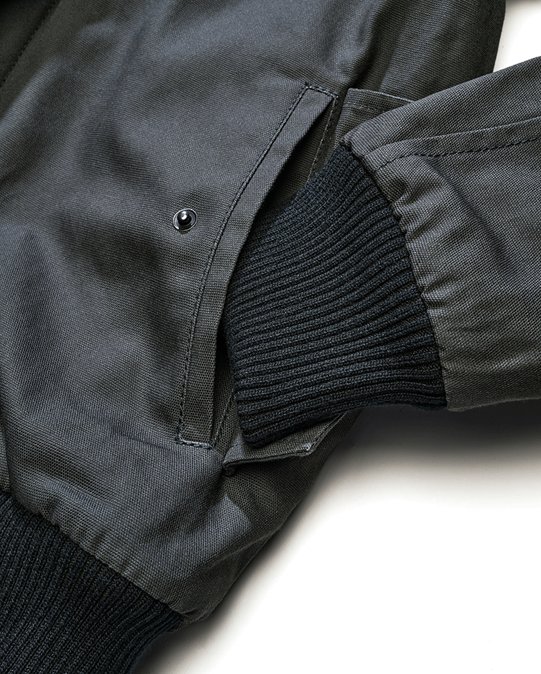 Brandit Kurzjacke Anthracite aus robustem Canvas mit Kapuze, Kordelzug, Teddyfellfutter und praktischen Taschen.