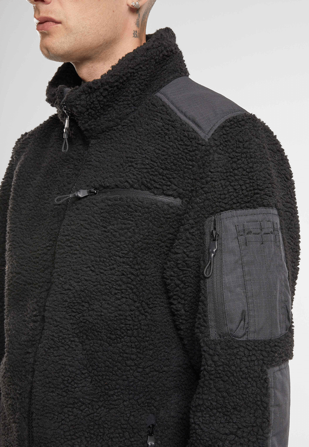 Brandit Teddyfleece Jacke in schwarz mit Ripstop-Einsaetzen, Reissverschlusstaschen, hohem Kragen und atmungsaktivem Meshfutter.