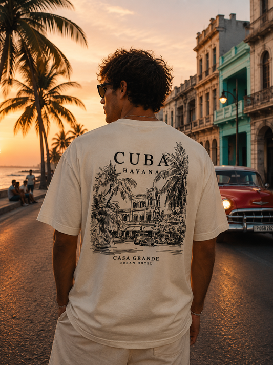 Model trägt Mister Tee Summer Stay Tee Vintage White bei Sonnenuntergang in Havanna mit Palmen und Vintage Car